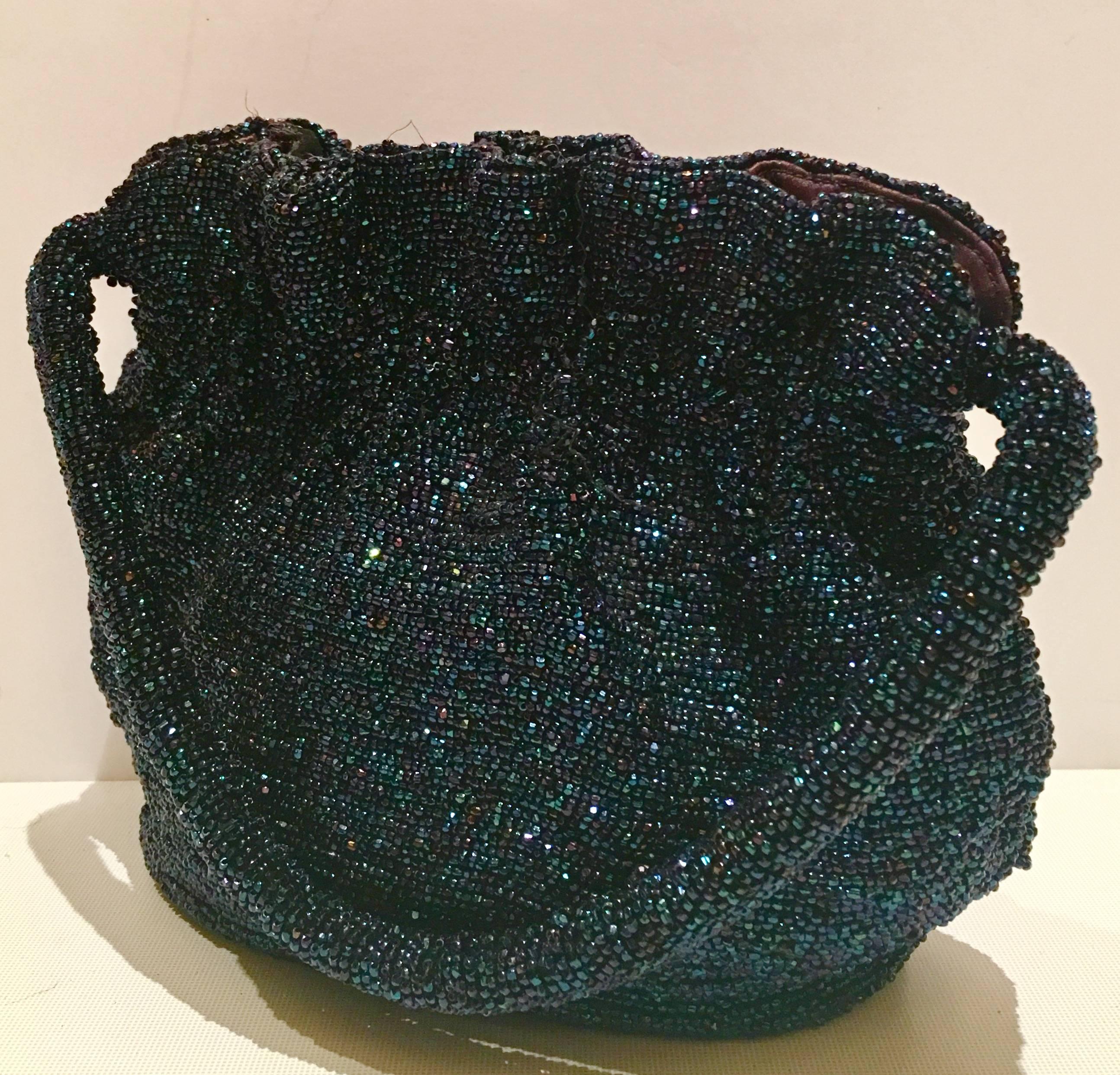  1940'S Bead Art Glass Iridescent Midnight Blue Handbag.  Features an accordion style cinch closure, fully s  lined in midnight blue satin with one interior side pocket, rope style shoulder strap and a hard reinforced bottom for support. 
Shoulder