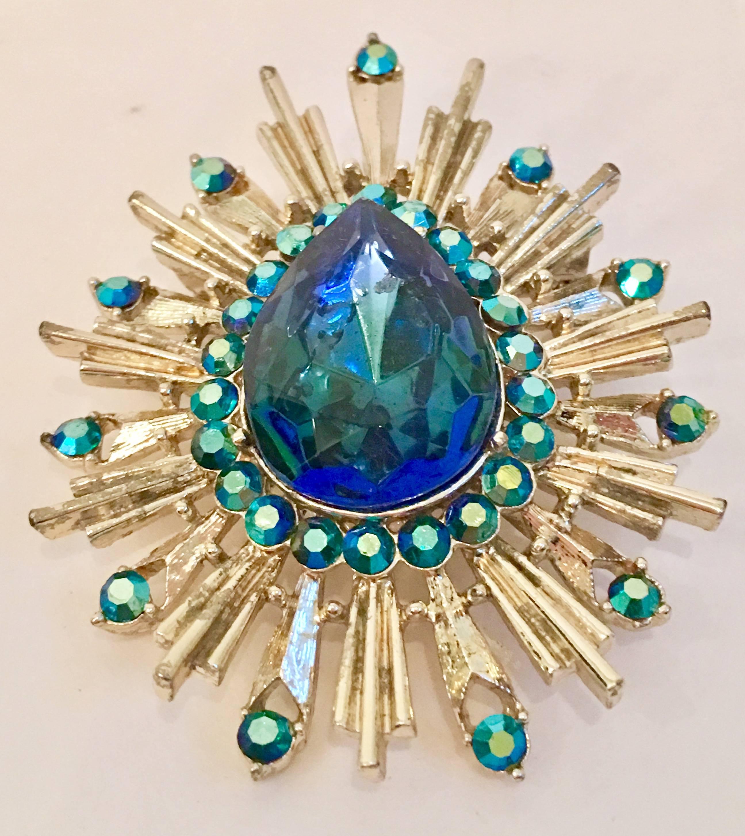 20th Century Large Starburst Convertible Brooch & Necklace Slide. Features gold tone plated metal and Austrian crystal rhinestone. Features one large central faceted blue sapphire stone approximately, 1