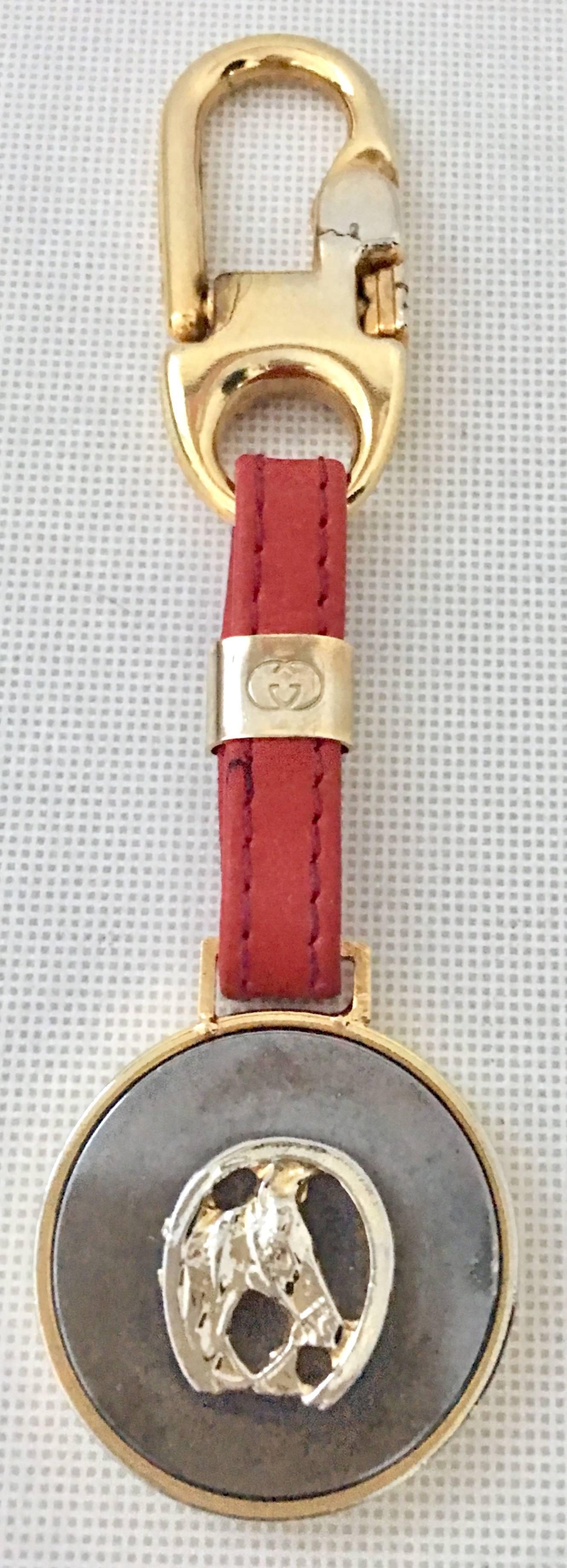 `Vintage Gucci Gold Plate & Red Leather Equestrian "Good Luck" Key Chain. This like new Gucci Italy gold plate and red leather key chain features a lovely weighted round disc of gold with a pewter color insert and raised horse shoe and