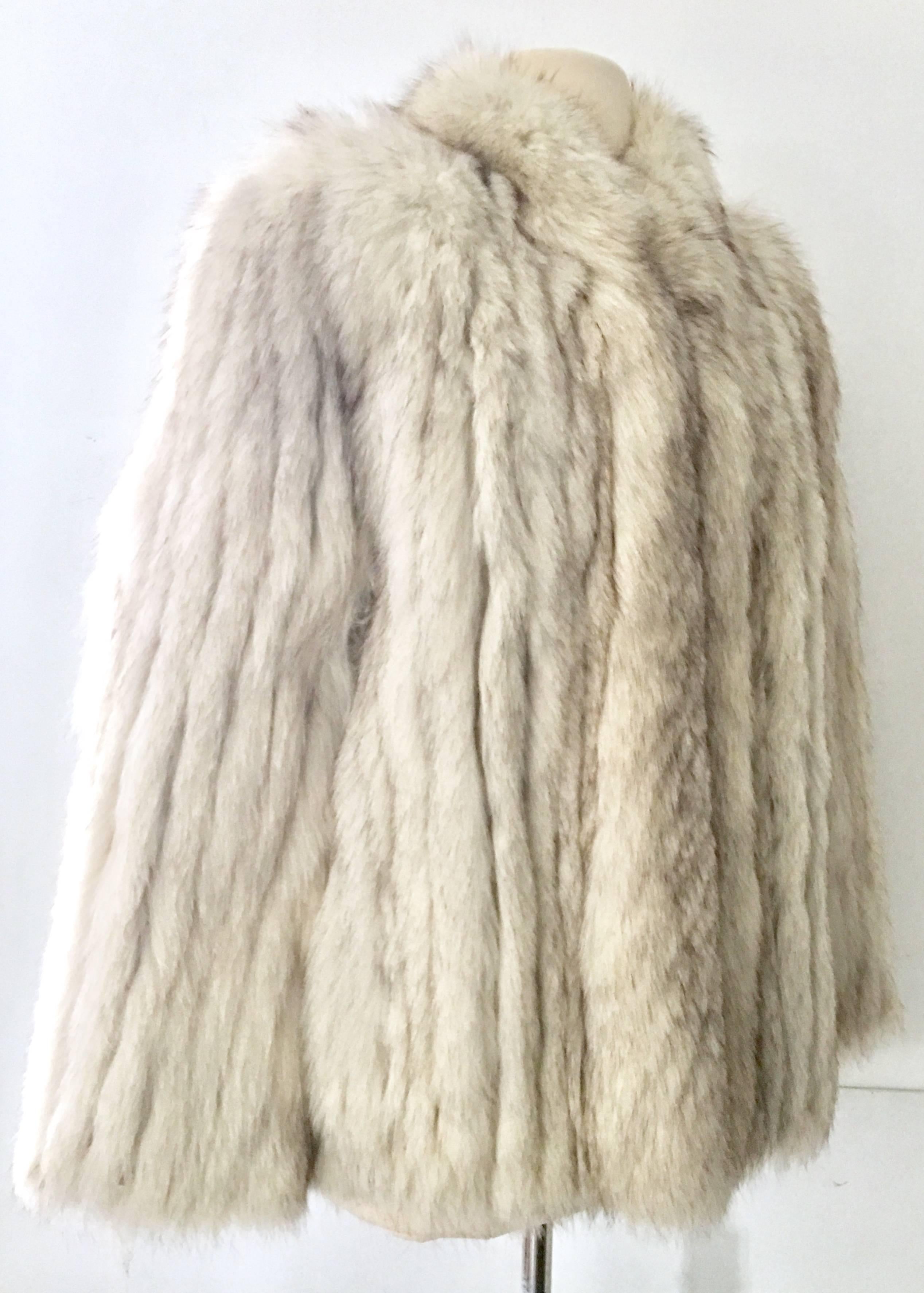 Vintage Winter White Silver Fox Jacket. This pristine jacket features, two side pockets and four invisible front closure hooks. Fully lined in silver satin with the original furrier tag in tact, Saga Fox-Size Medium.