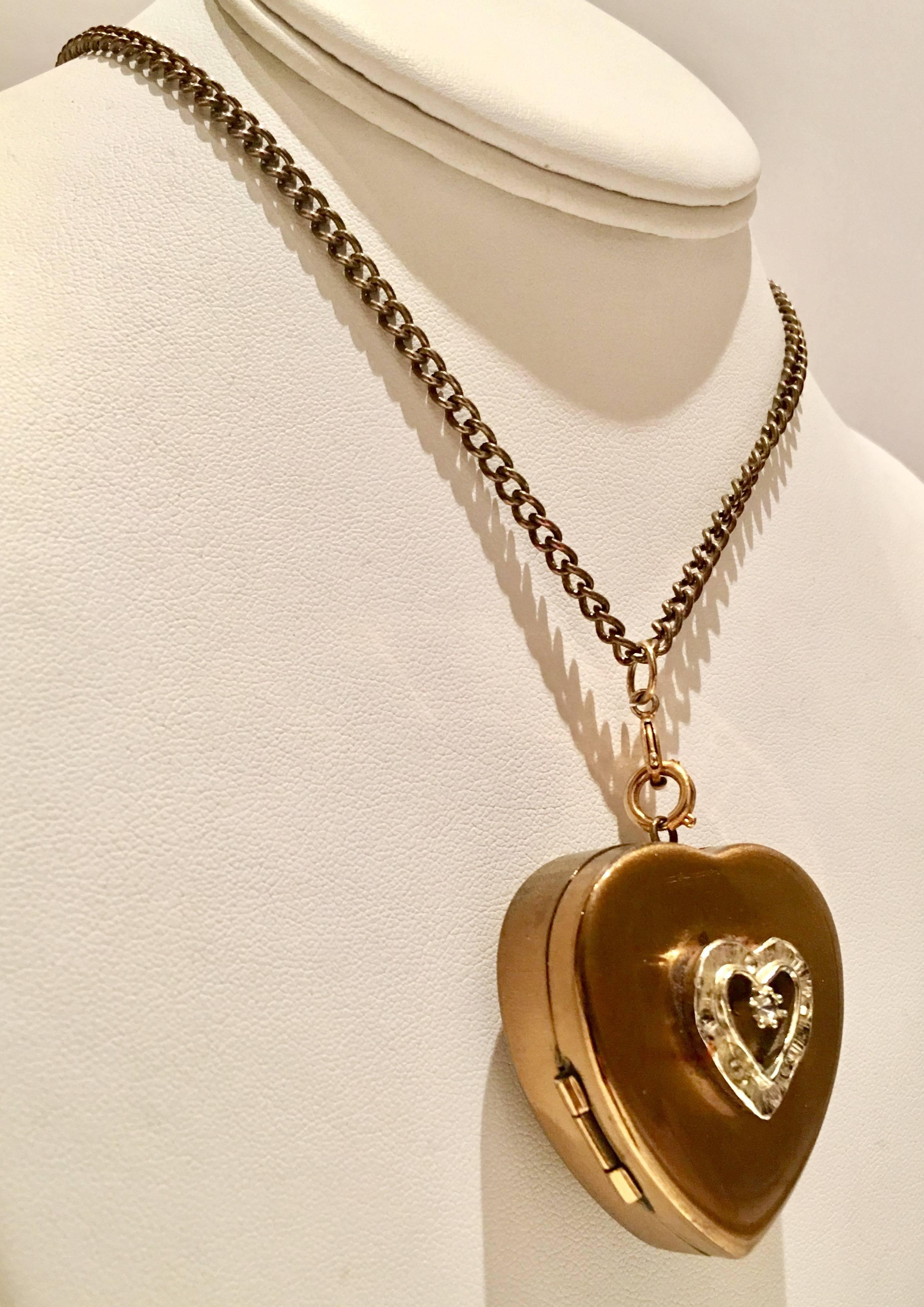 1950'S Darling gold bras heart picture locket music box pendant necklace. Signed, Japan. The heart locket has a central crystal clear rhinestone and five crystal clear surrounding rhinestones set in silver tone metal. The chain has one locking clasp