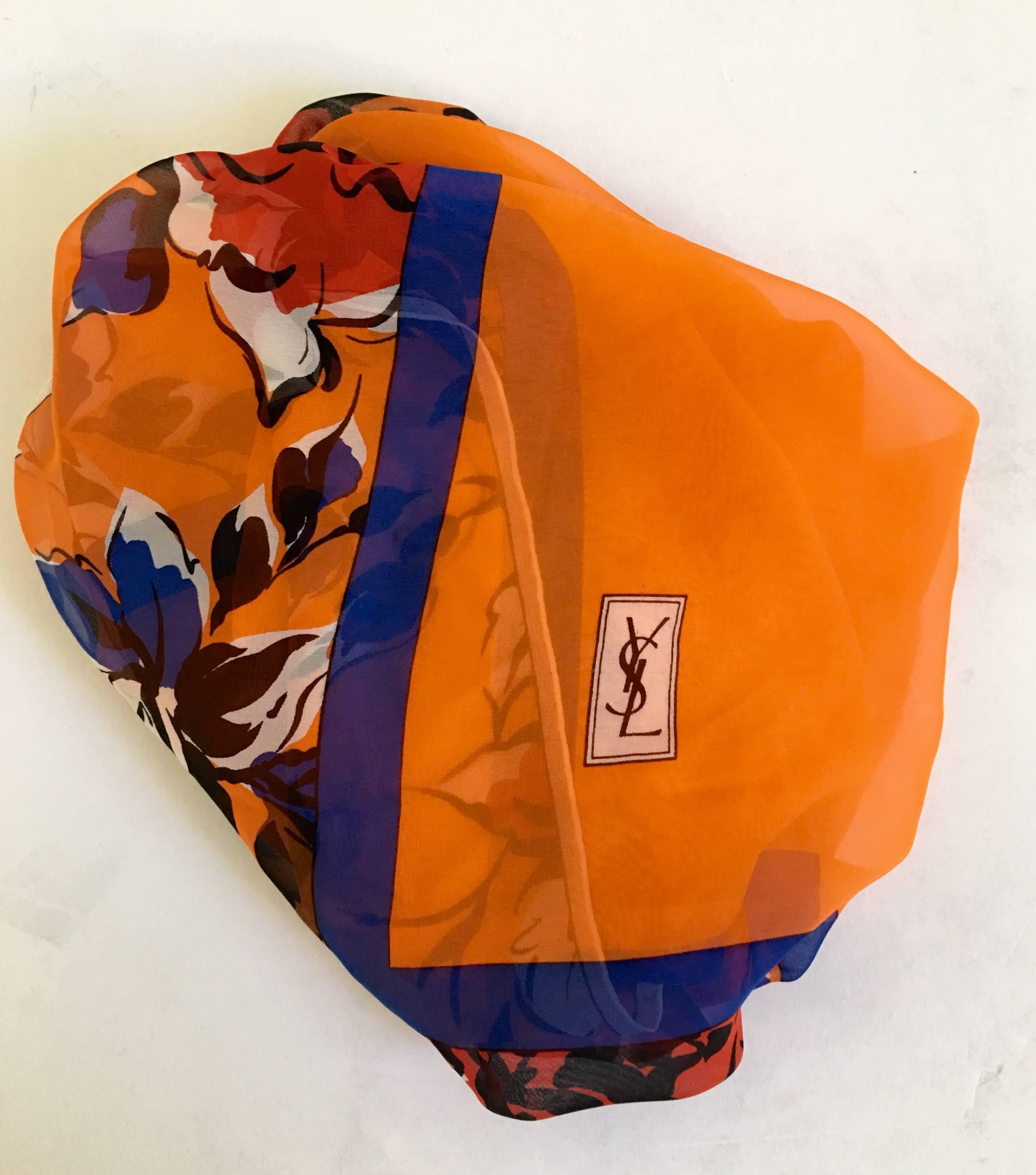Rare 1970'S Yves Saint Laurent Silk Chiffon silk scarf . Features a ground of vibrant orange with electric blue, red, white and black floral motif border. Hand rolled edge detail, 34
