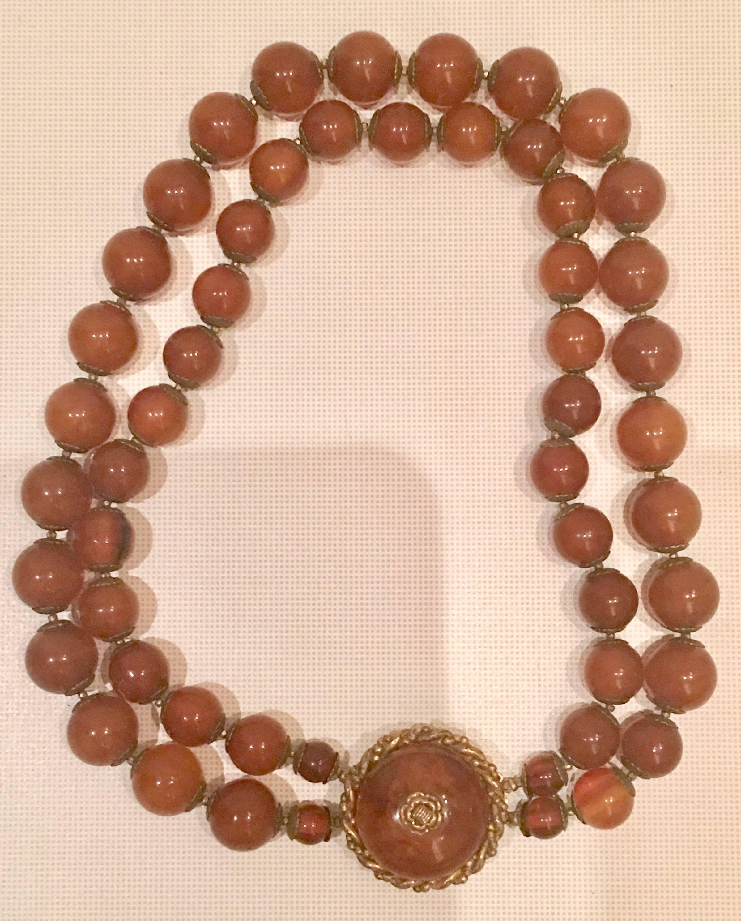 Mid-Century signed Miriam Haskell two strand amber glass bead choker style necklace. Features iconic Russian gold detail. Signed on clasp, Miriam Haskell. Center ornament measures, 1.13