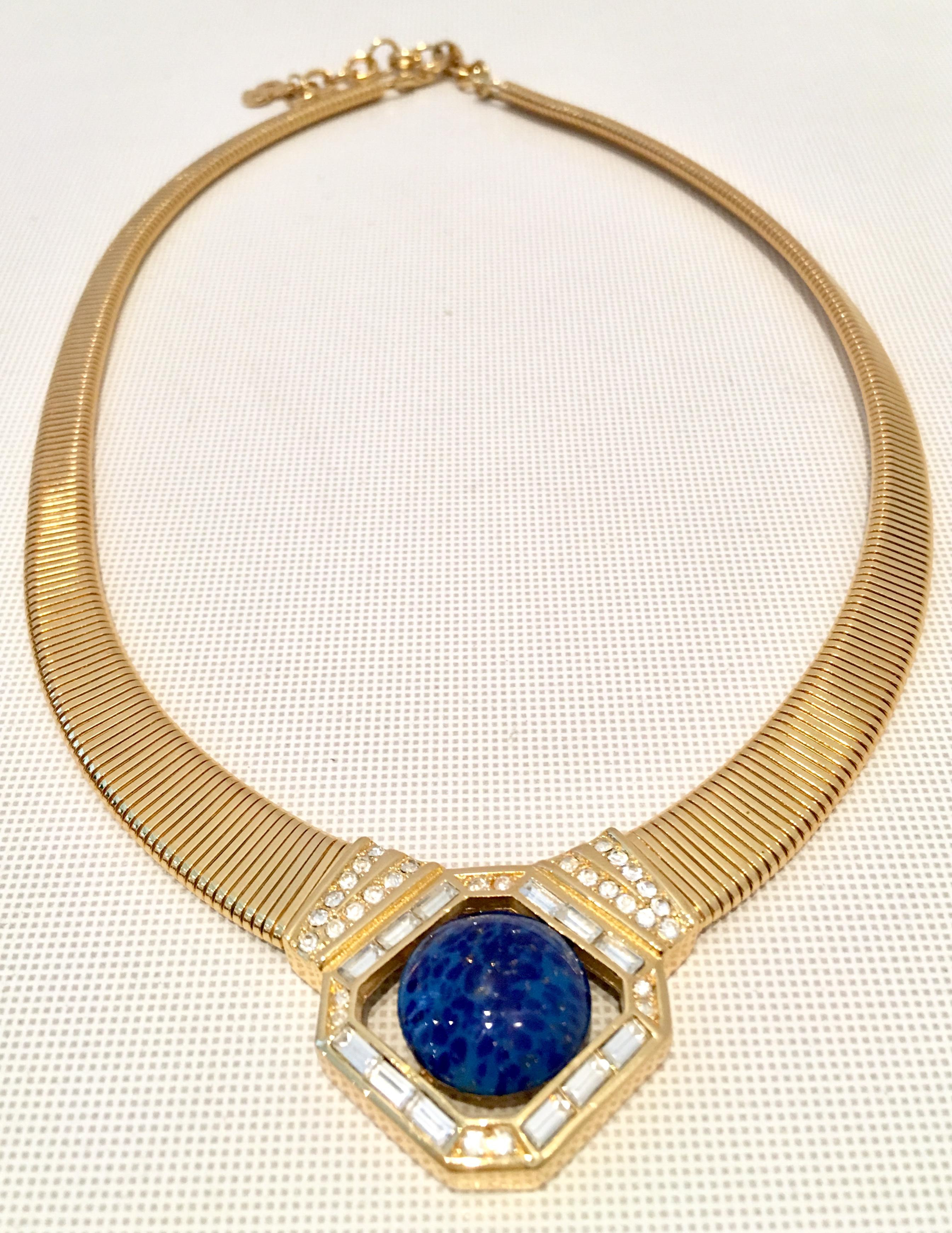 20th Century Gold Plate Choker Style Necklace By, Christian Dior. Features a gold plate textured necklace with a large central faux cerulean blue lapis lazuli round inch stone surrounded by Swarovski crystal clear paste set rhinestones. The fold