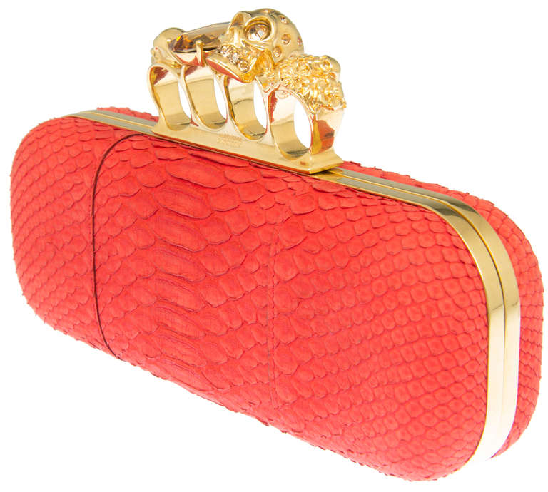 This is a gorgeous box style clutch made with red snakeskin and a gold tone knuckle duster handle decorated with skulls and jewels.
