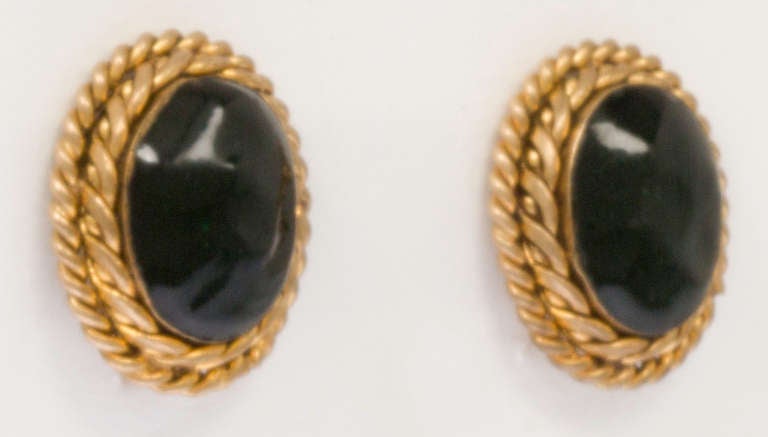 These are early Classic CHANEL, featuring a deep green poured glass cabochon surrounded by gold gilt roping. Signed