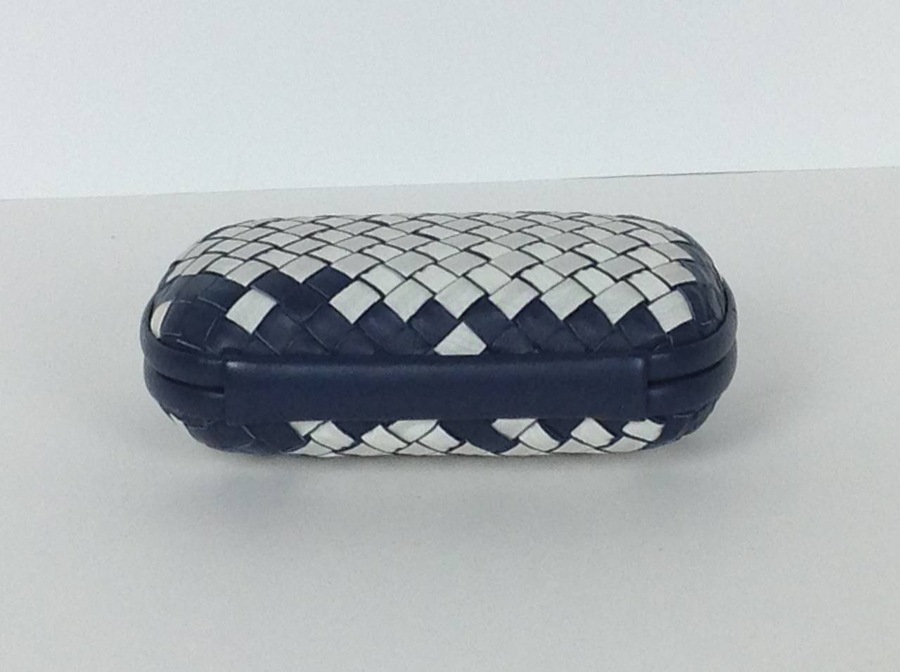 Navy leather woven with white grosgrain ribbon in signature Intrecciato weave, by Bottega Veneta.
Hardshell body, trimmed in navy leather. Rounded corners. Knotted hinge clasp.
Lined in suede, stamped Bottega Veneta.
4