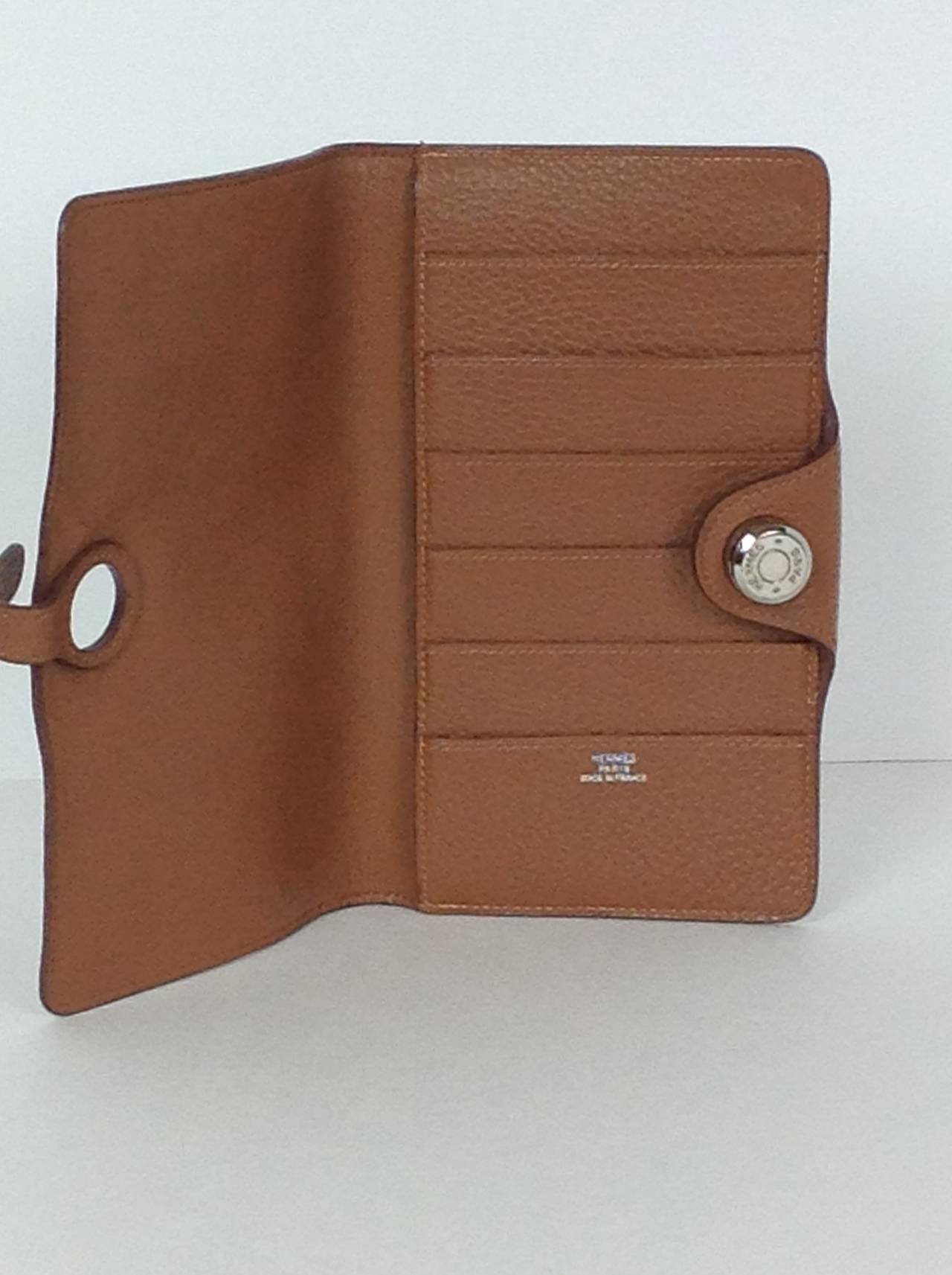 Hermes Dogon wallet in tan togo leather.  
Lined in tan lambskin.  6 slip pockets (for credit cards, ID etc), and one large pocket for bills. Stamped HERMES Paris Made in France.
Closes with fold over flap. Clou de selle tab strap closure, that