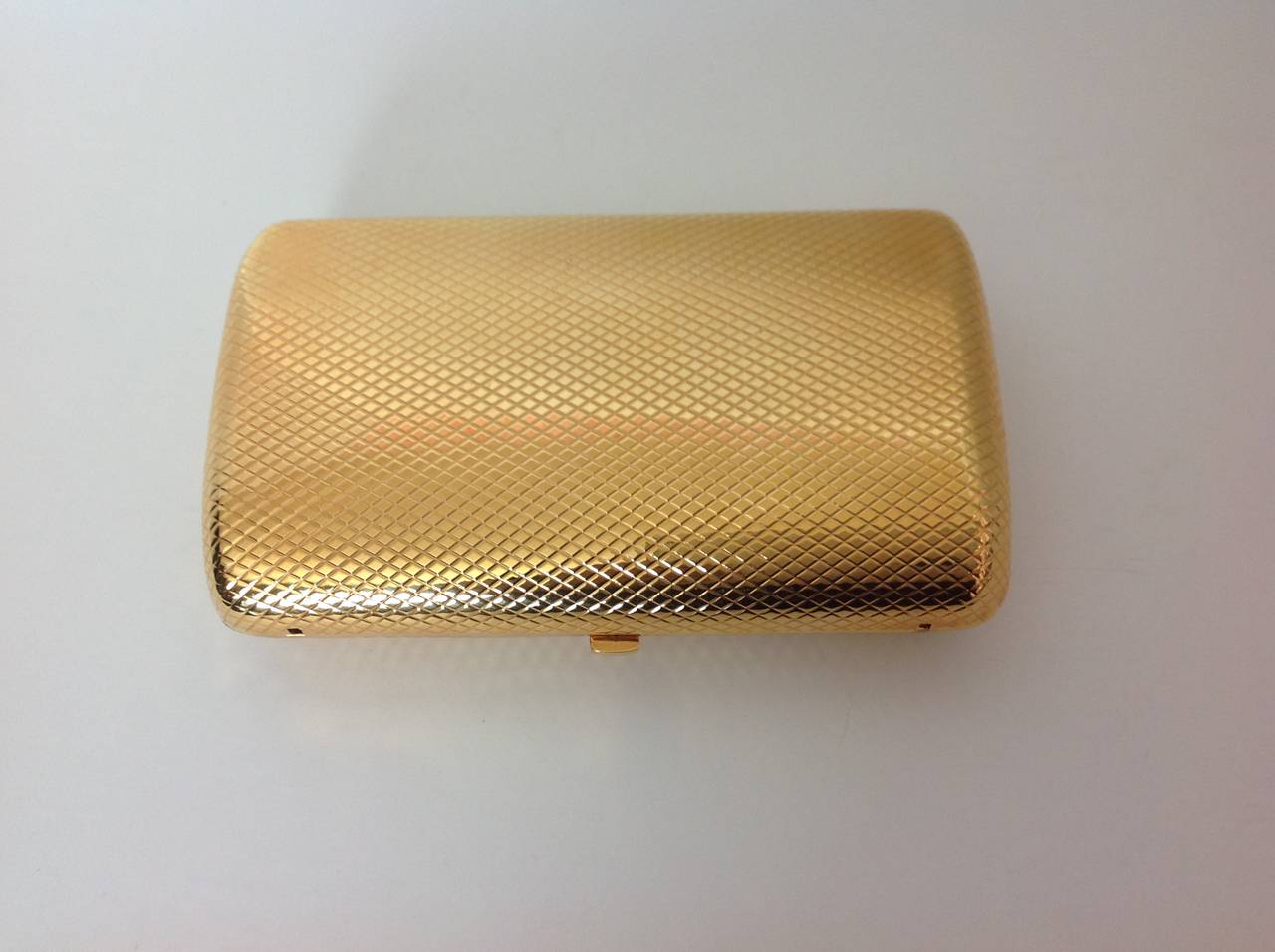 Monica Rich Kosann (jeweler) 24K goldplated minaudière clutch.
Pyramid guilloche pattern.  
Perfect condition,still has tags! (tag reads $4855.)  NO dents (difficult to photograph), no scratches, no smell.
Lined in marigold calfskin, with a MRK