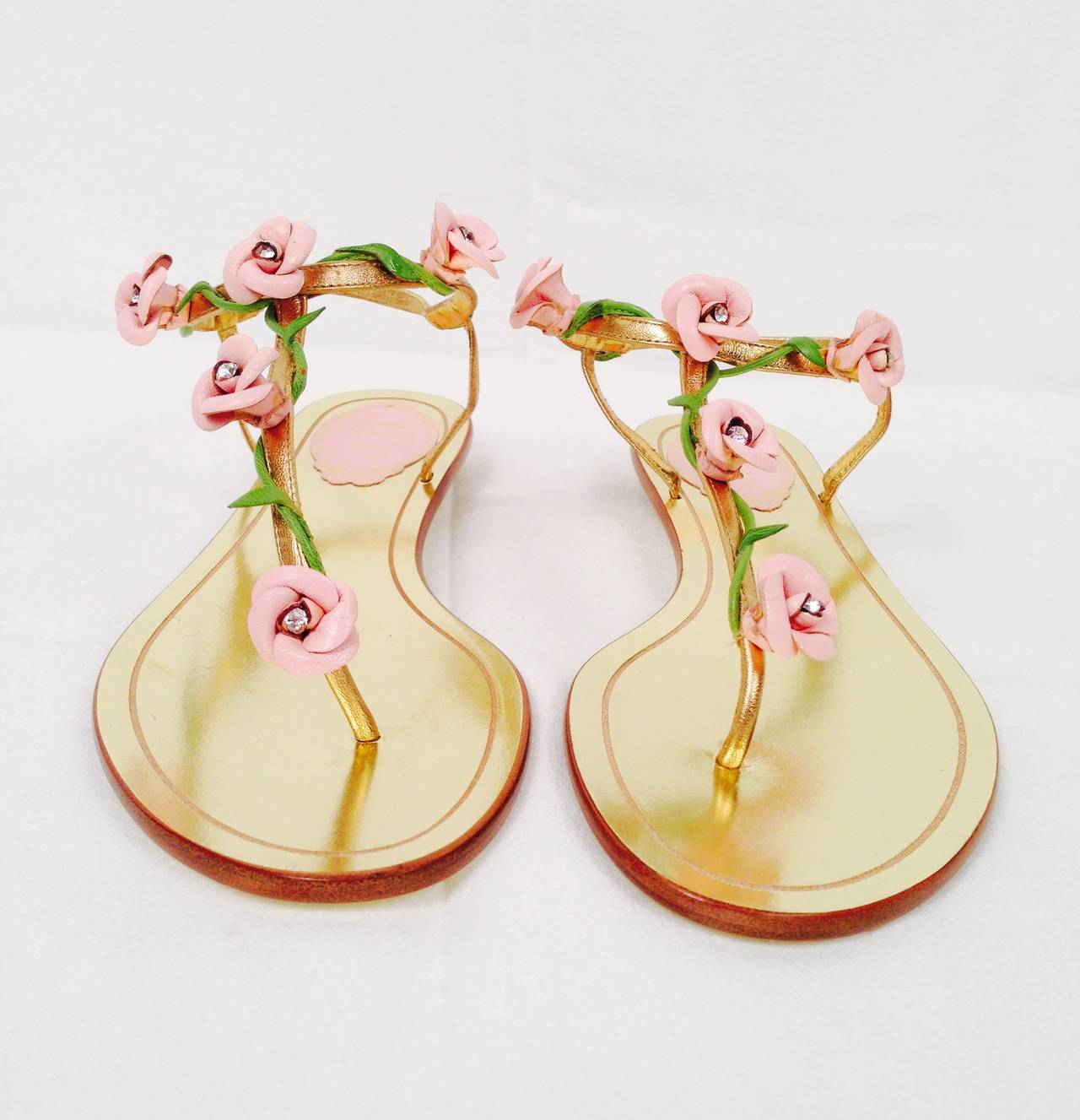 All that glitters is gold in these metallic gold leather thong sandals from Rene Caovilla!  Sandals feature delicately hand-crafted pink leather rosettes on a vine embellished with one center crystal. Metallic leather insole AND sole.  What a sweet