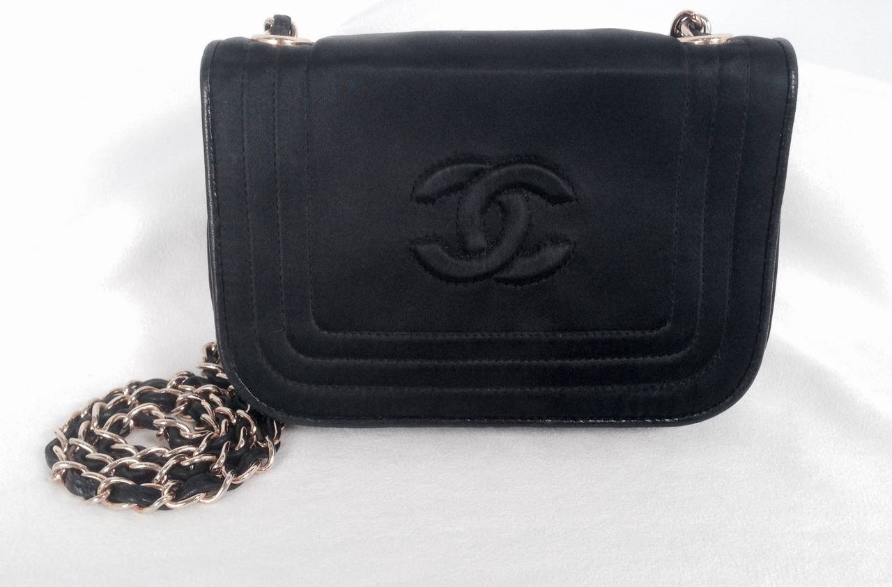 Crafted between 1986 and 1988, this vintage 1980s Chanel black satin evening shoulder bag more than impresses contemporary audiences!  Features full single flap, single gold tone chain strap, and snap closure.  Finished with lambskin leather piping.
