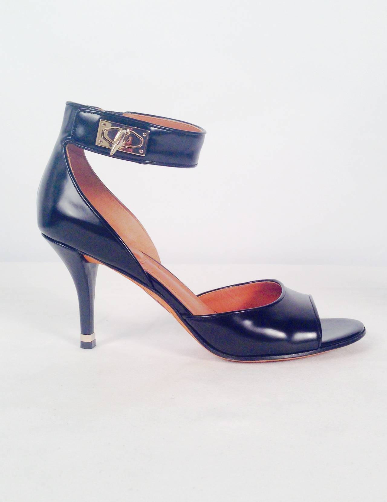 Givenchy Black Polished Calfskin PeepToe Heels With Ankle Straps are worthy of the runway in any fashion capital.  Features gold tone heel accent and abstract turn lock on ankle strap.  Classic yet current!  Padded insole ensures comfortable