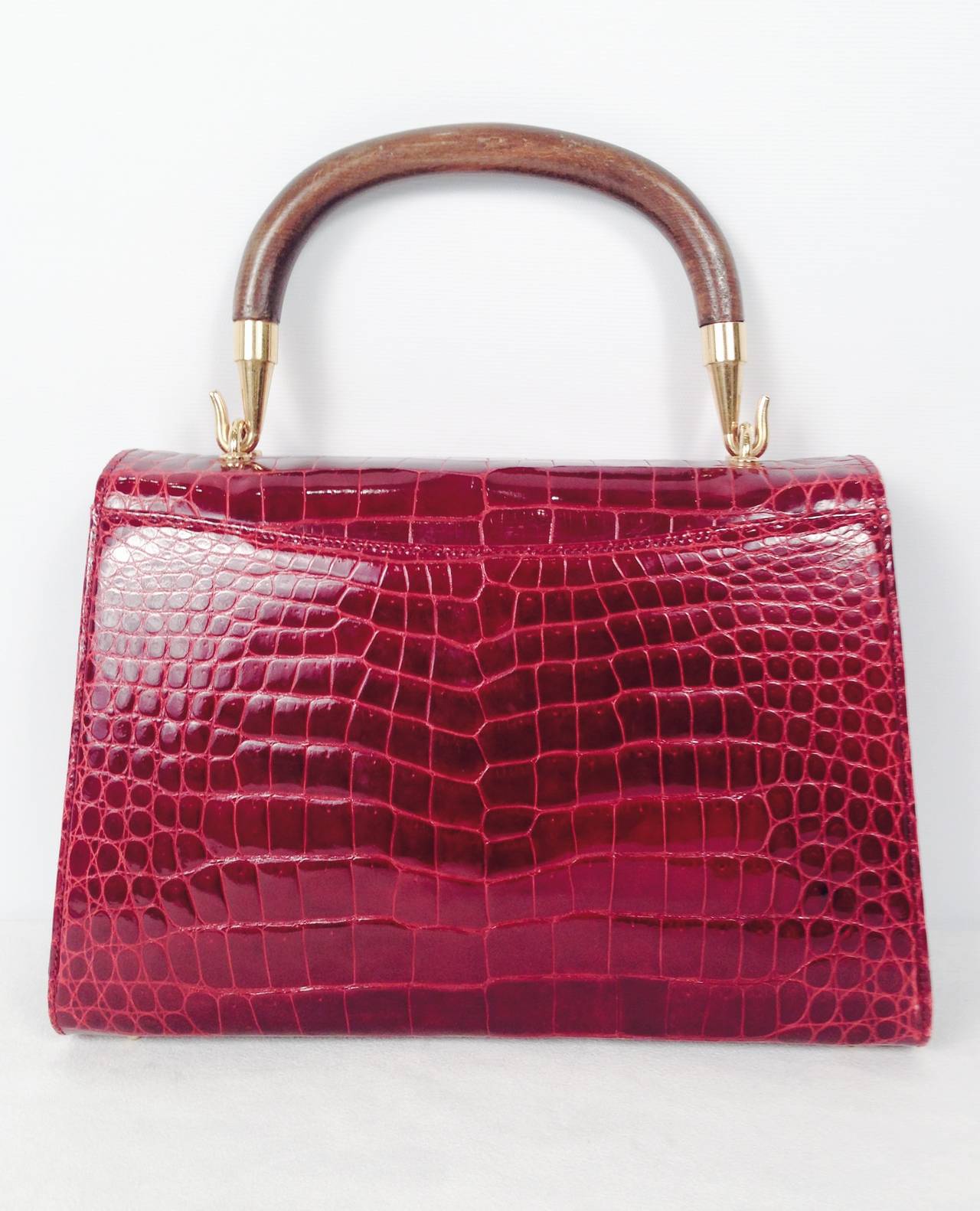 Vintage Gucci Burgundy Crocodile Handbag is an ode to the exalted craftsmanship that defines the house of Gucci.  This handbag perfectly blends form, function, and fashion!  Soft, supple burgundy crocodile is paired with wood and gold tone hardware.