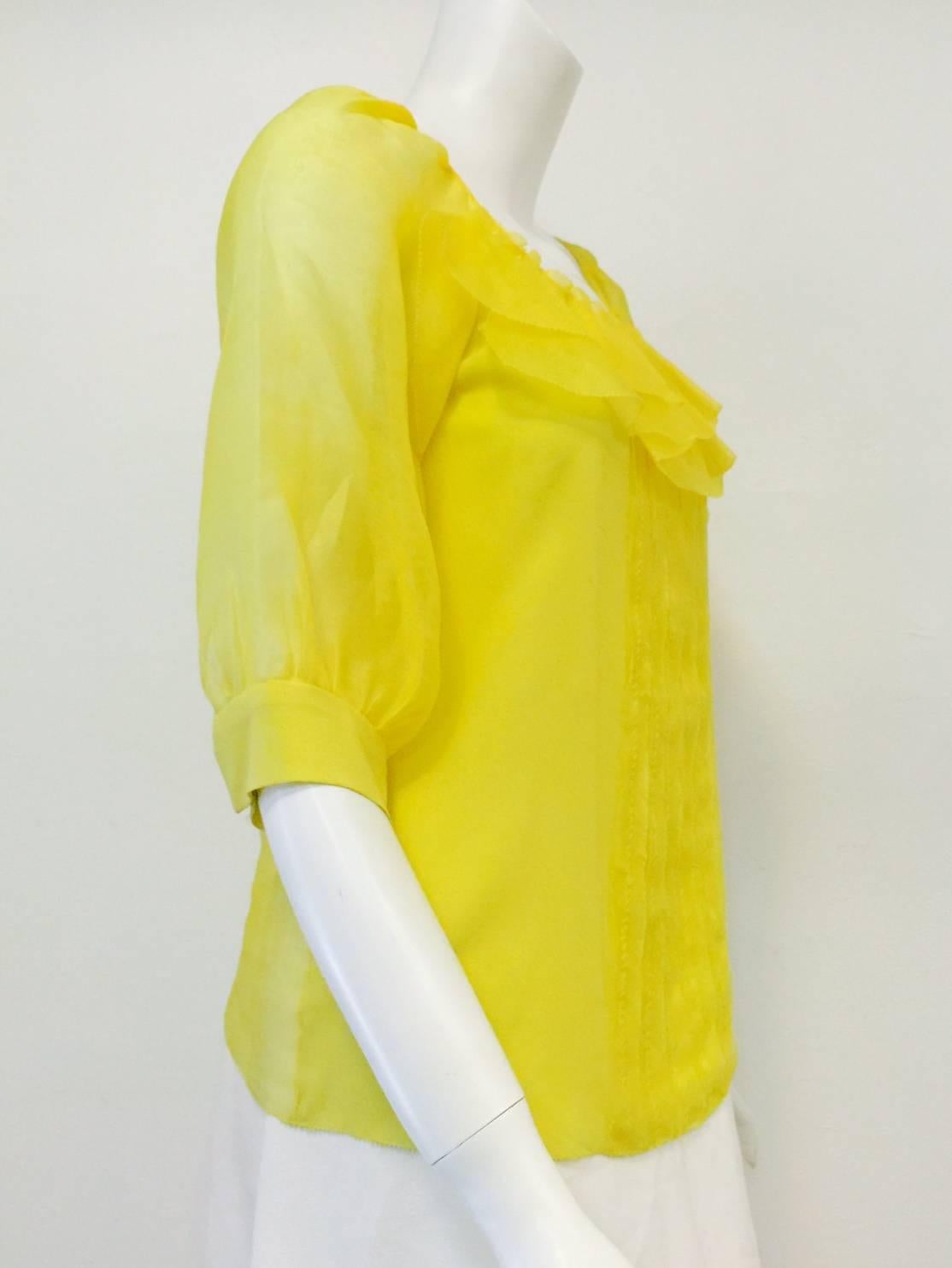 Silk Lemon Blouse is pure Oscar de la Renta...feminine, vibrant, and classic!  Features exquisite fabric in an unforgettable shade of yellow, round neckline and vertical exposed seam front detail.  Ruffles at neckline?  Buf of course!  Elbow length,