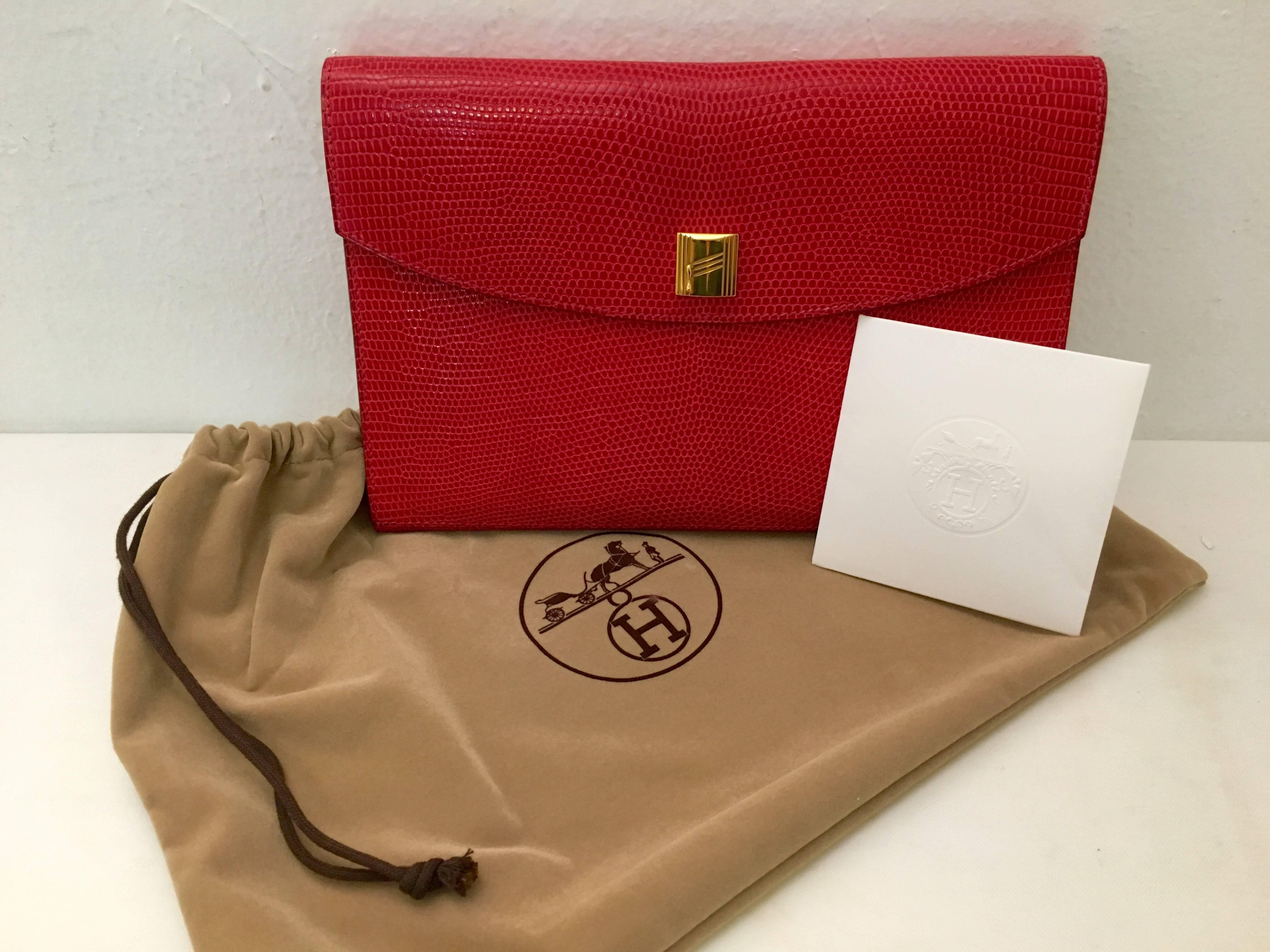 Hermes handbags are wildly collectable and hold their value like none other!
This pristine red lizard clutch is elegance in simplicity.  A distinctive gold tone stylized "H" covers the snap down closure. Red leather inside.  Unmarred,