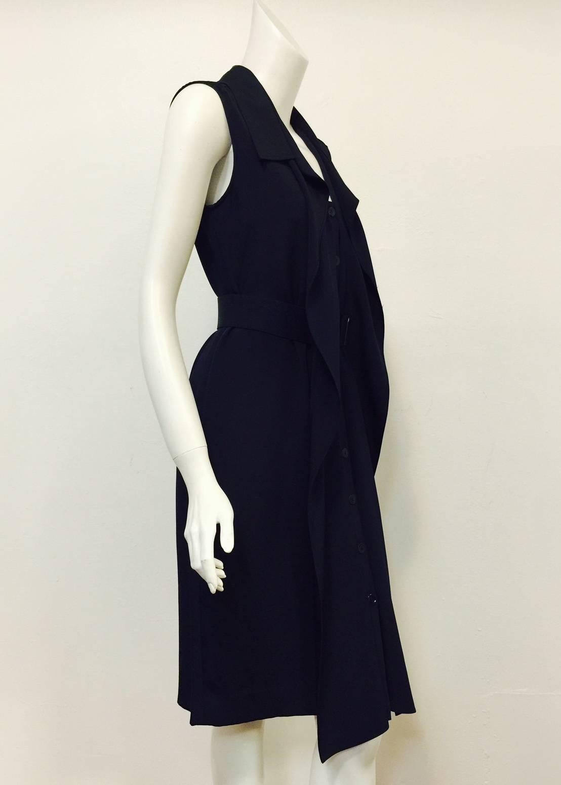 Oscar de la Renta Navy Belted Dress is ageless and timeless. Features exquisite silk, sleeveless design, and slightly above the knee length.  Reminiscent of a men's shirt, dress has 9 button front closure, cutaway collar and tiered, rear box pleats!