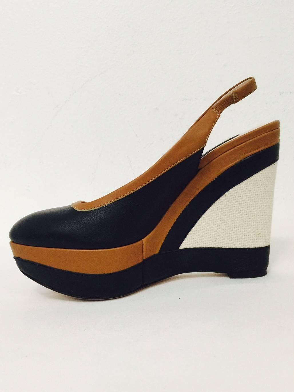 Transition into fall with these elegant Escada Navy and Toffee Leather Wedges!  Features modern platform styling, slingback design and leather lining, soles, and insoles.  The finishing touch, natural burlap details the heels!  Made in Italy. 