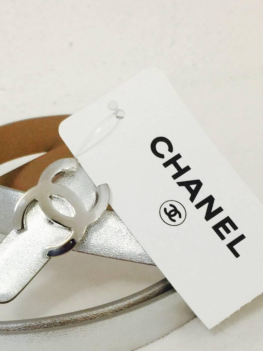Coveted Chanel Leather Skinny Belt perfectly complements Mademoiselle's classic, effortlessly tailored looks!  New With Tags, belt features ultra-luxurious silver metallic leather exterior and tan lining.  The finishing touch?  Chanel's signature