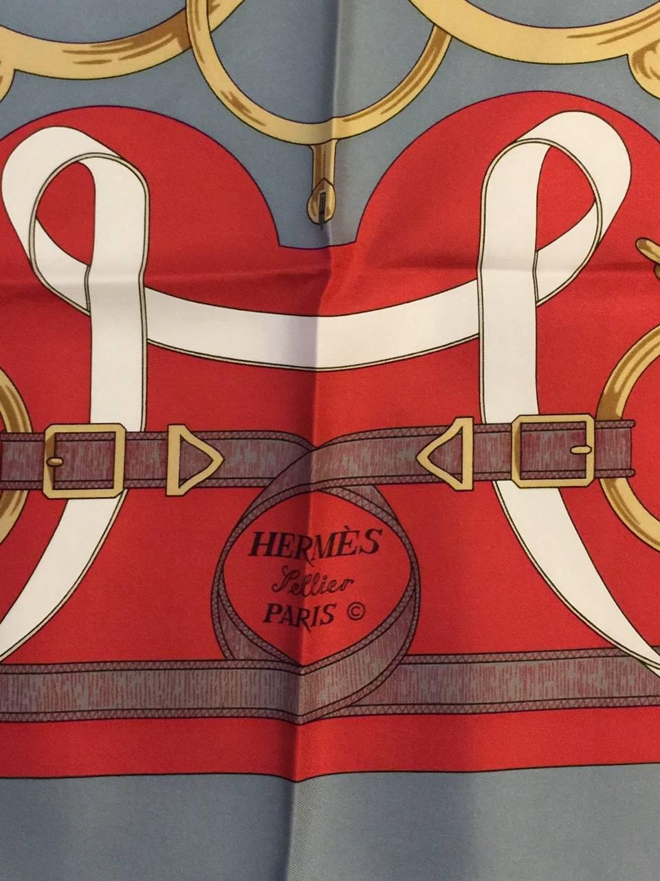 Designed by famed artist Henri d'Origny, Eperon d'Or was first issued in 1974. Hermes 100% SilkTwill Scarf was reissued in 2010 and features a modern and crisp color combination of steel grey and brick red metal balanced with gold and white.  