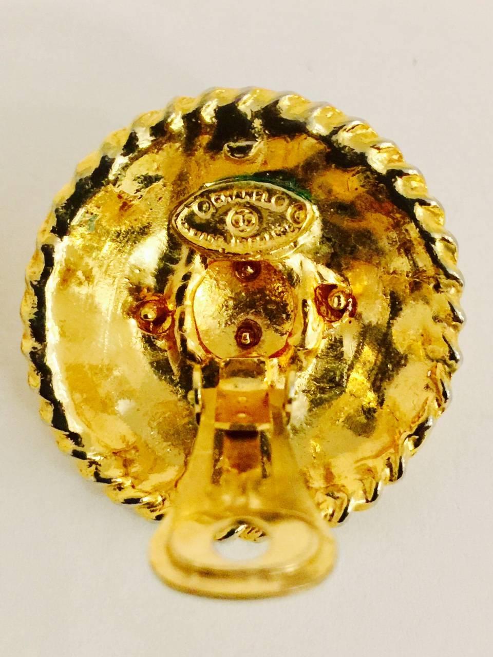 A must for all Cocoholics!  Recognizable at a glace.  Round, partially domed with rope edge border.  Raised letters spell out CHANEL PARIS with the ever classic CC logo center.  Clip on earrings in gold tone. 1971-1980  Properly hallmarked.