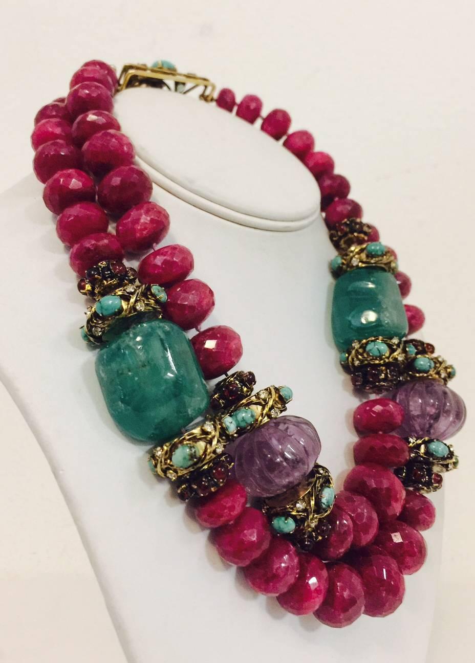 Every Iradj Moini design is one of a kind.  This important piece was designed as two rows of graduated, faceted ruby beads, spaced by large tumbled natural emeralds and textured blackened yellow metal spacers, set with cabochon turqouise, red glass