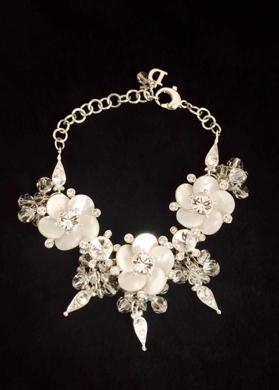 From the world renowned Dior comes this delightful bracelet in silver tone featuring three flowers crafted in shell mother of pearl.  Swarovski crystals abound!  Dangling sections feature clear faceted beads and, yes, more Swarovski crystals. Secure