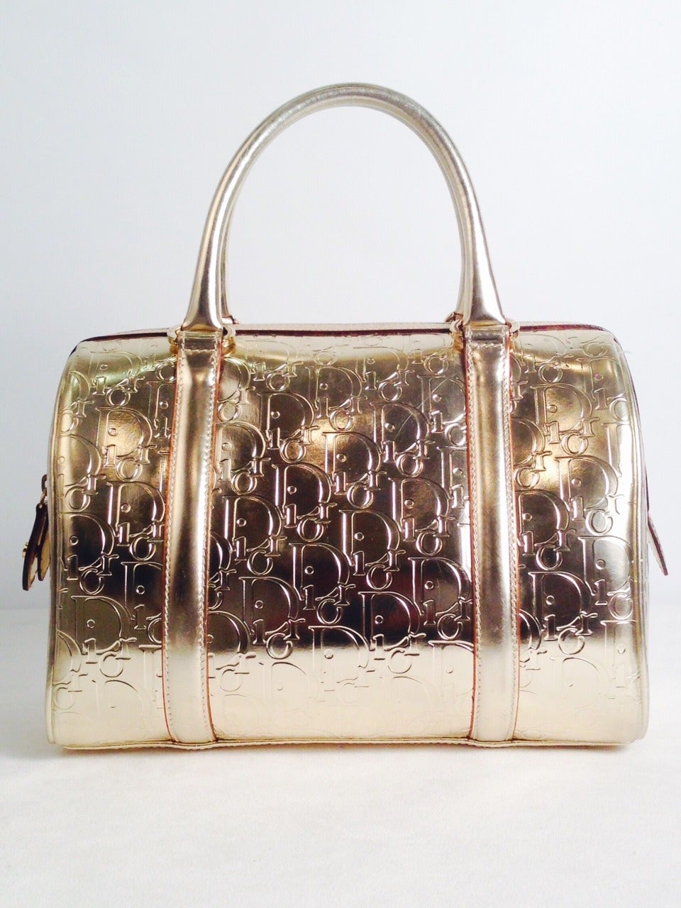 Christian Dior Gold Metallic Leather bag gives the impression of pure 24K gold!  Features include signature logo embossed all over, top zipper, and double handles.  Interior is crafted from luxurious linen and cotton blend fabric and has one