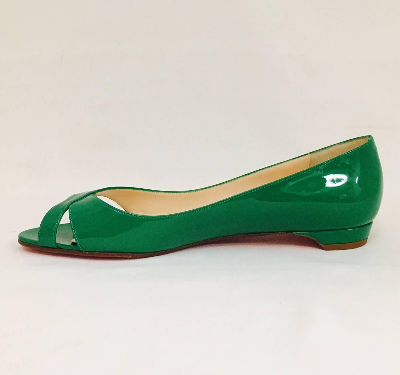 Christian Louboutin is so much more than skyscraper high heels!  These flats are crafted from luxurious Emerald Green Patent Leather and feature criss-cross vamps with cutouts and peep toes.  Beige and suede lining and sculpted heels finish the