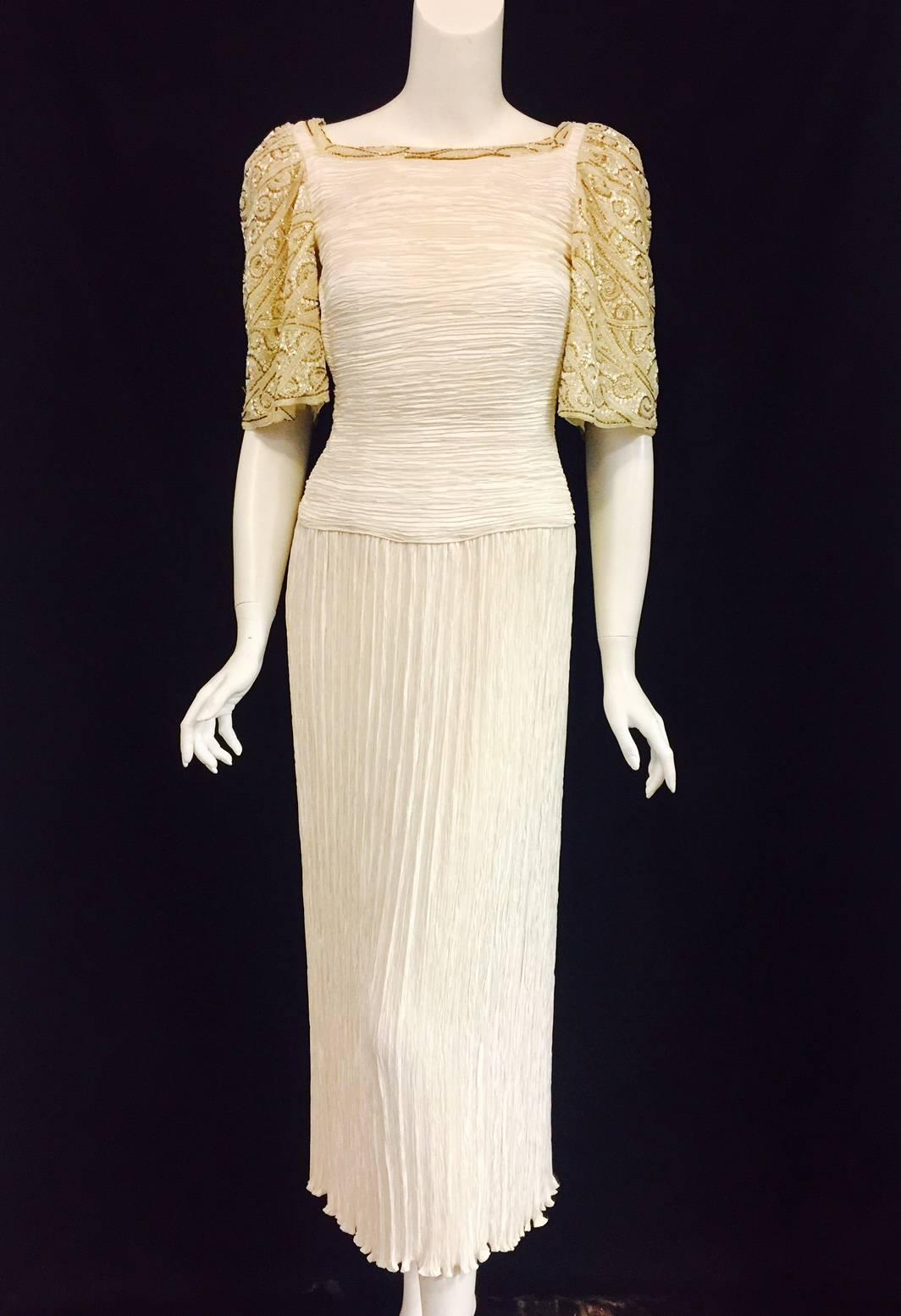 The gown is created in the iconic and instantly recognizable Mary McFadden Marii pleating. The neckline and short bell sleeves are embellished with beige, gold, white and Ivory beads. This gown is quintessential McFadden, who was inspired by ancient