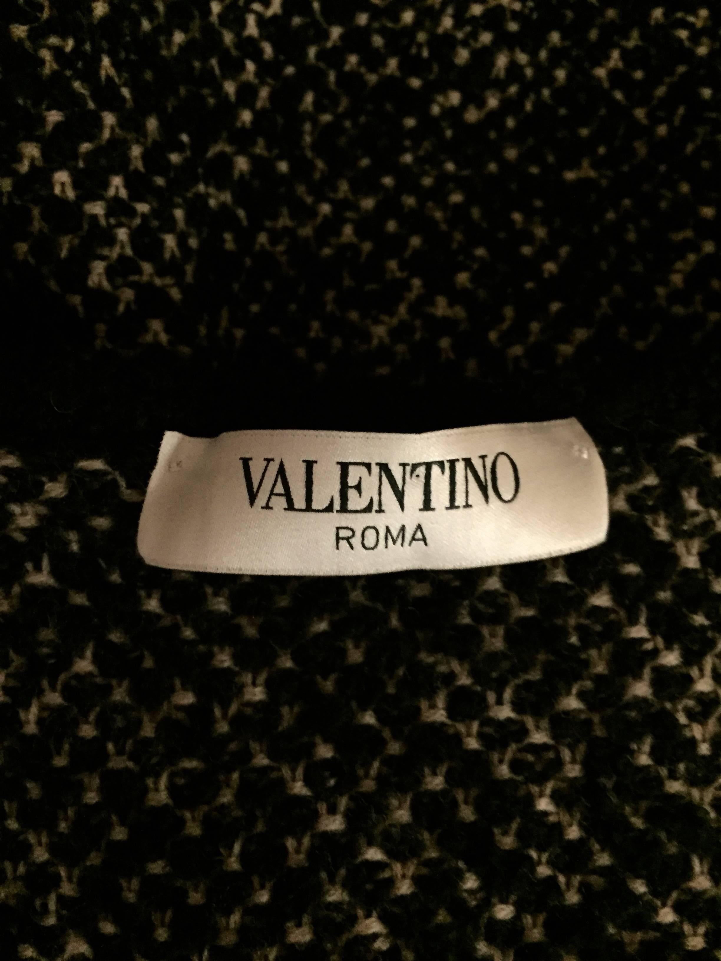 This Valentino tweed black and grey wool sweater jacket has 4 hidden snaps for closure at front and decorative black trim around round neckline, front closure and waist.  Complementary pleats accentuate jacket below the waistline.  Unlined.  Will