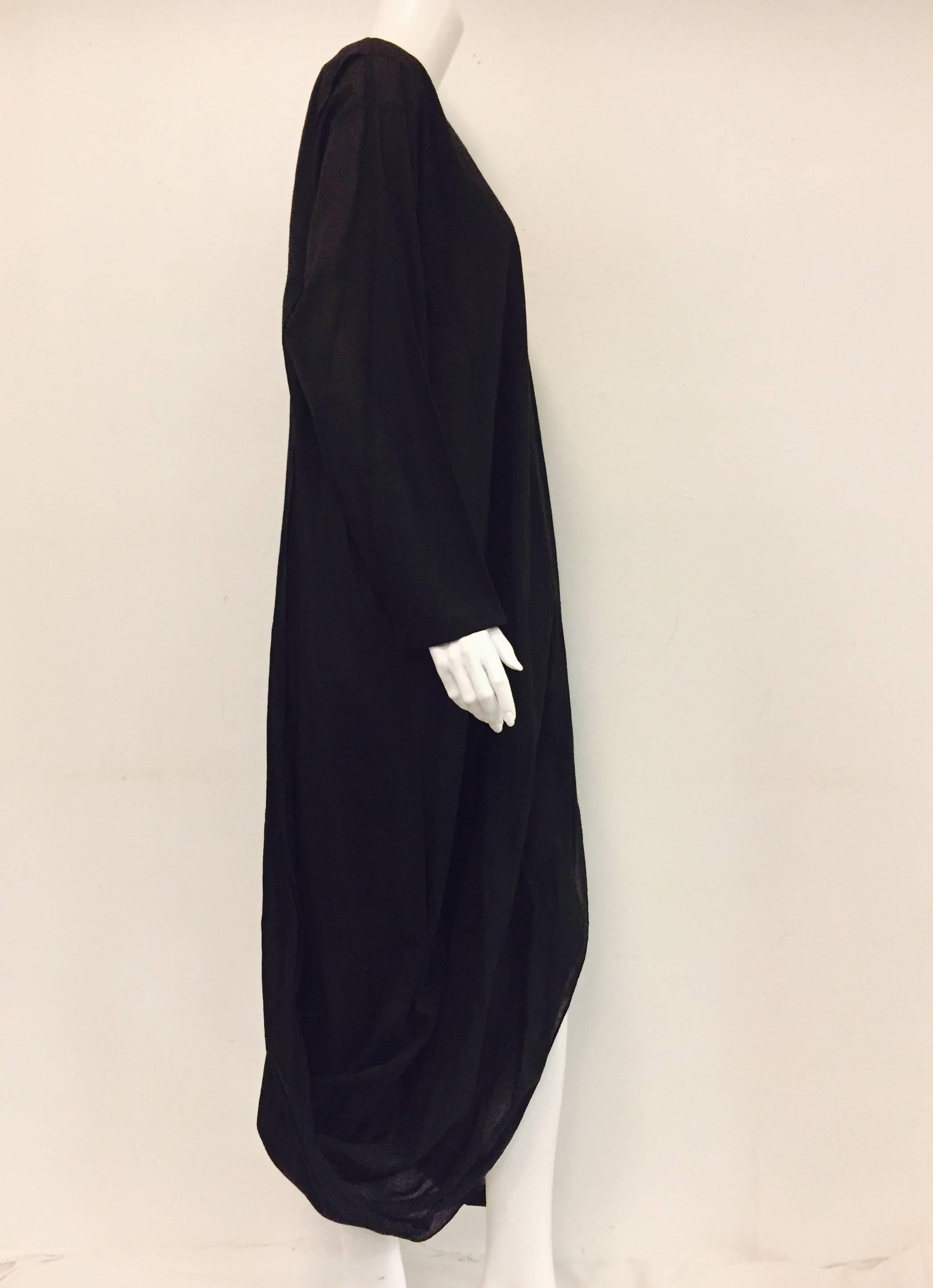 Issey Miyake creates a casual yet intriguing unstructured design with this loose fitting long black dress.  It is creative with a slit from shoulder to hem and up the back of the dress.  Long sleeves with no collar.  Made in Japan.