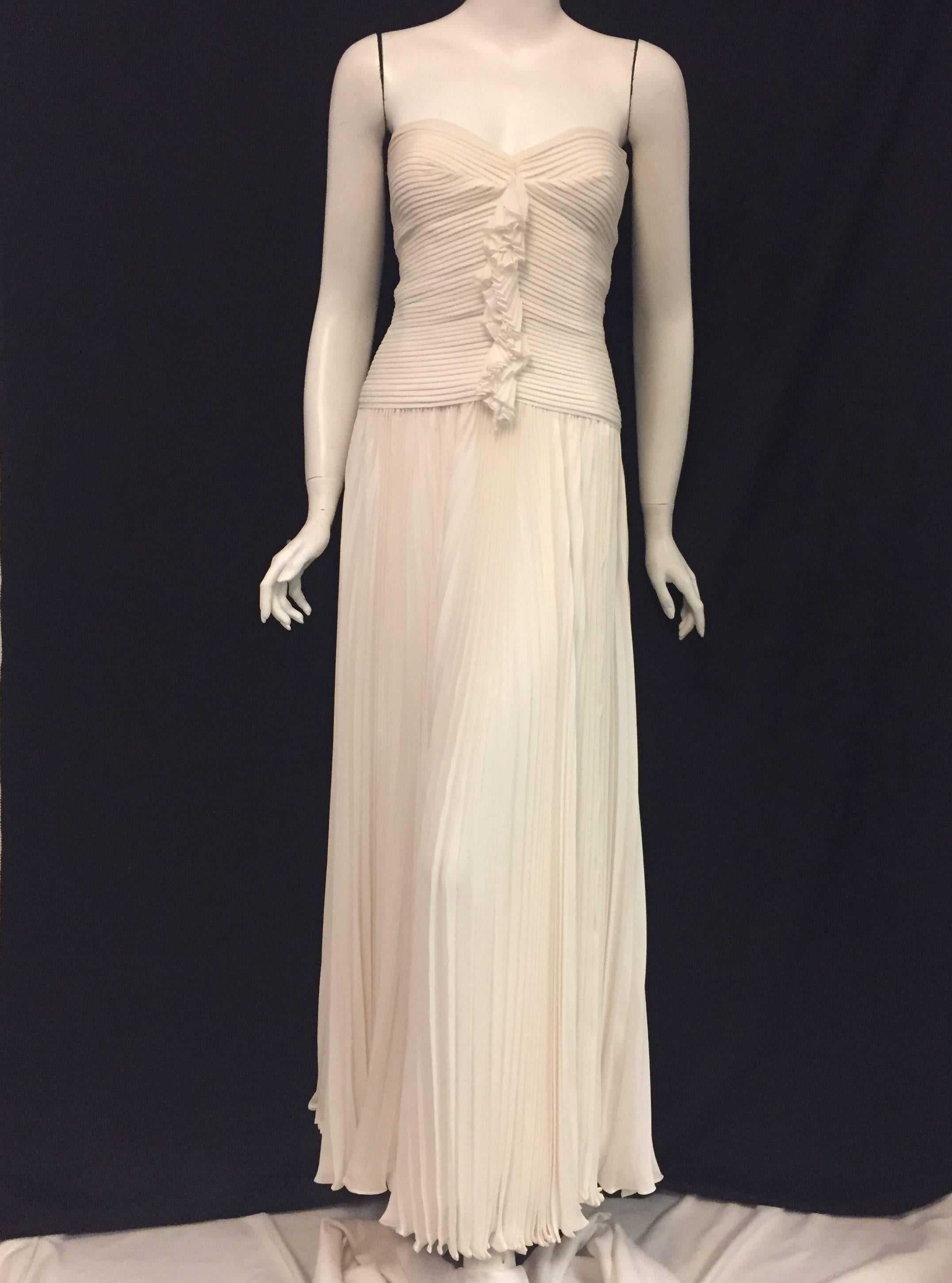 Oscar de la Renta's outstanding gown with horizontal pleats on the bodice and vertical accordion pleats on the skirt creates a flirty style dress.  The bodice is ruched at front coming down from the center of the sweetheart decolletage to the