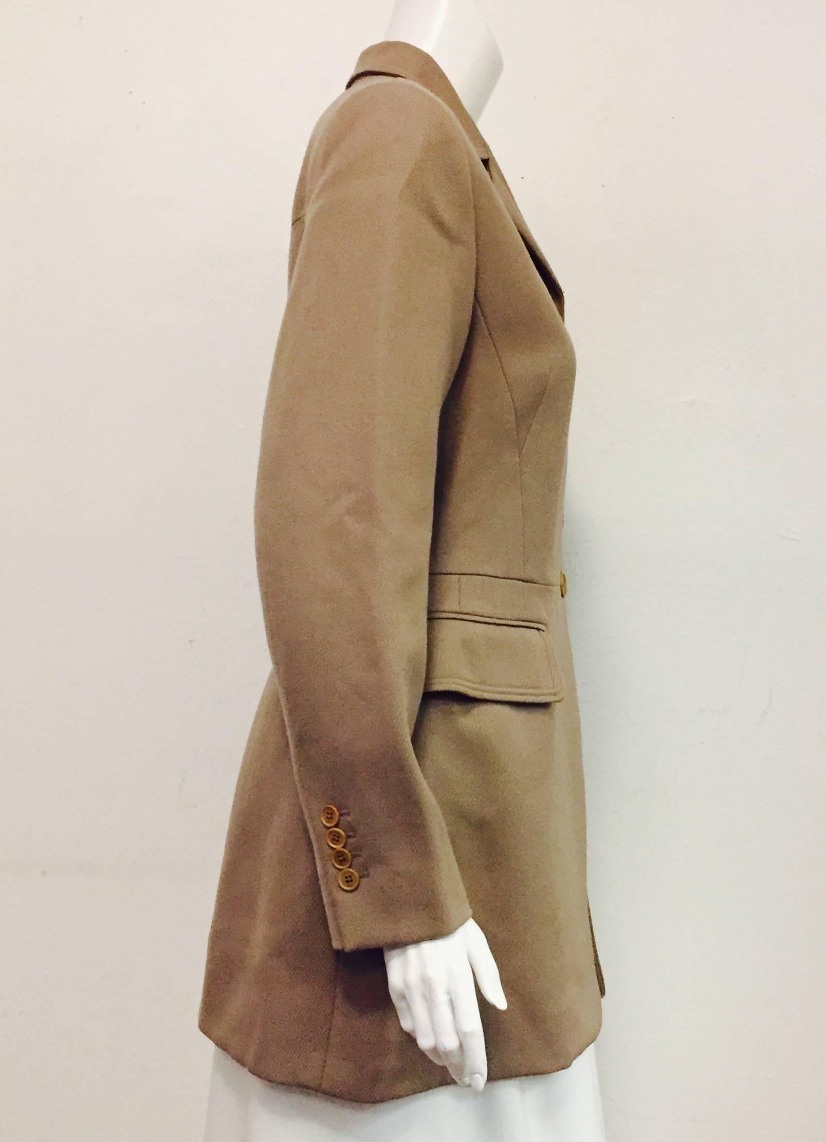 Hermes' elegantly shaped taupe woman's riding jacket features exquisite details allover, including 4 button single breast  construction,  notch collar and 2 flap pockets at hip.  Chest has single slit pocket.  Jacket length extends to mid thigh and