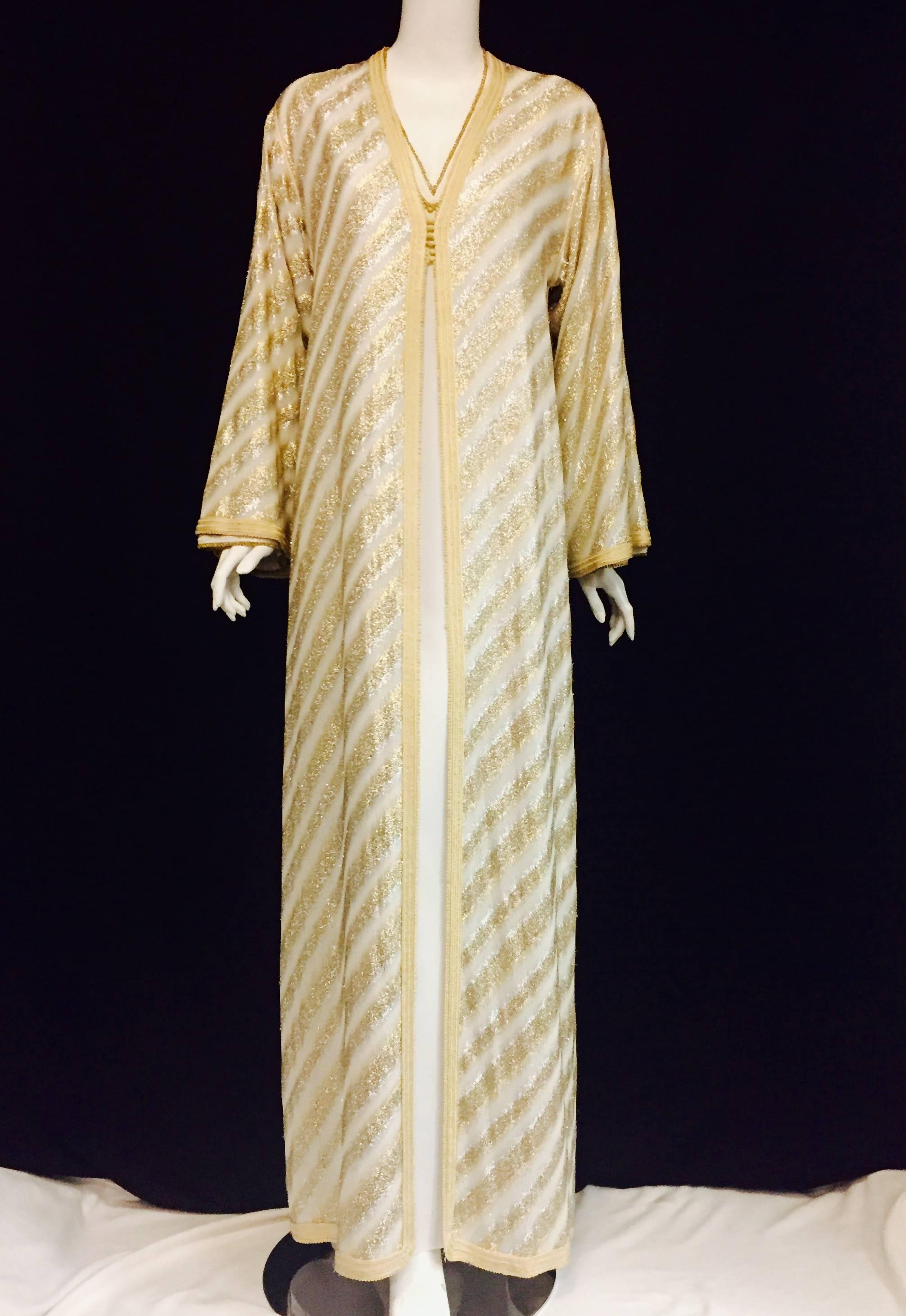 Vintage Celine Paris 2-piece Caftan ensemble is crafted from exquisite white and gold lame.  The inner dress is white silk with gold tone grecian style cord on neckline and at cuffs of long sleeves.  The outer dress/coat is constructed with white