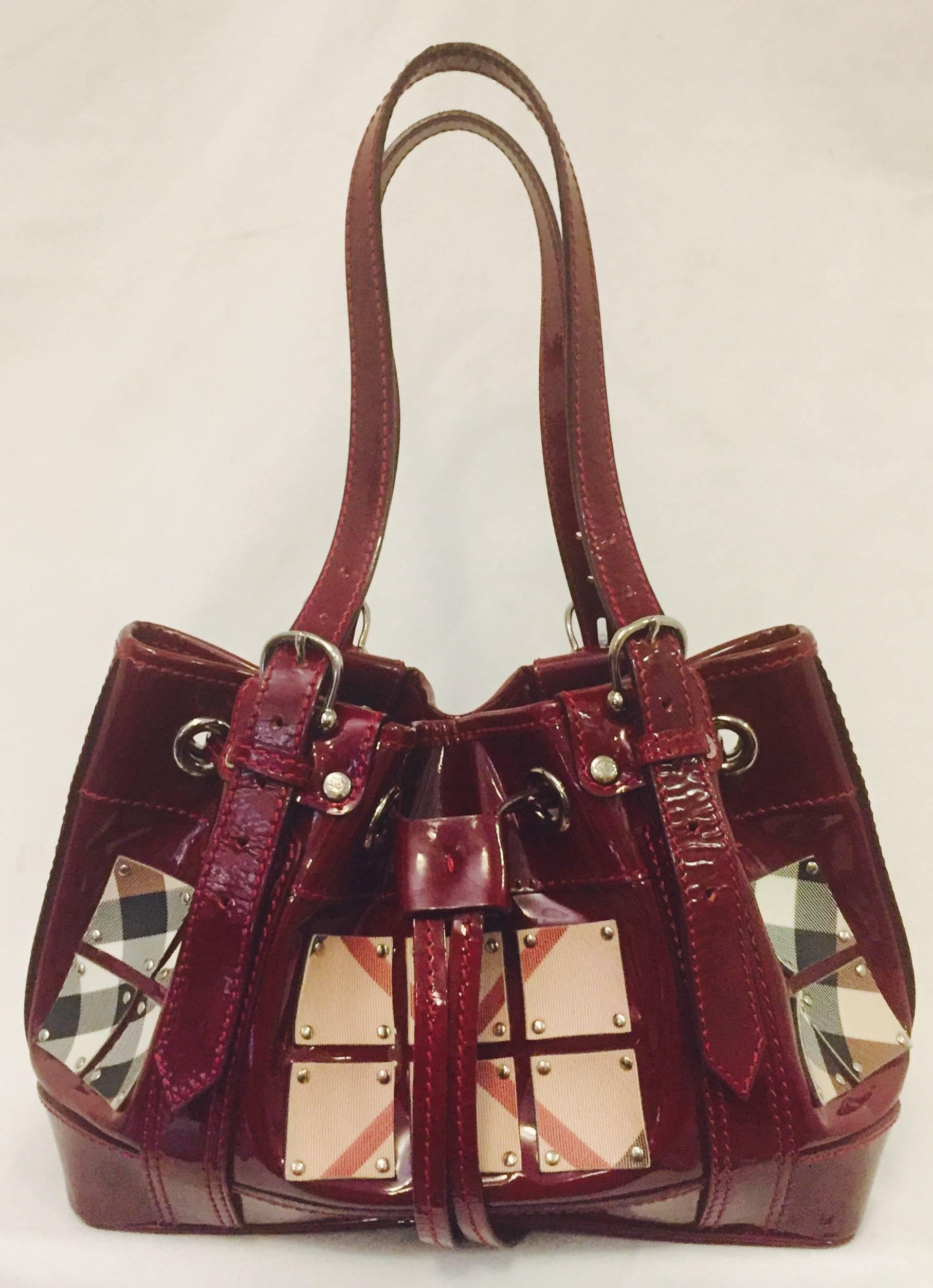 Burberry's Burgundy Large Satchel is decorated with mini coated canvas squares and silver nail studs.  The squares are composed of iconic Burberry 