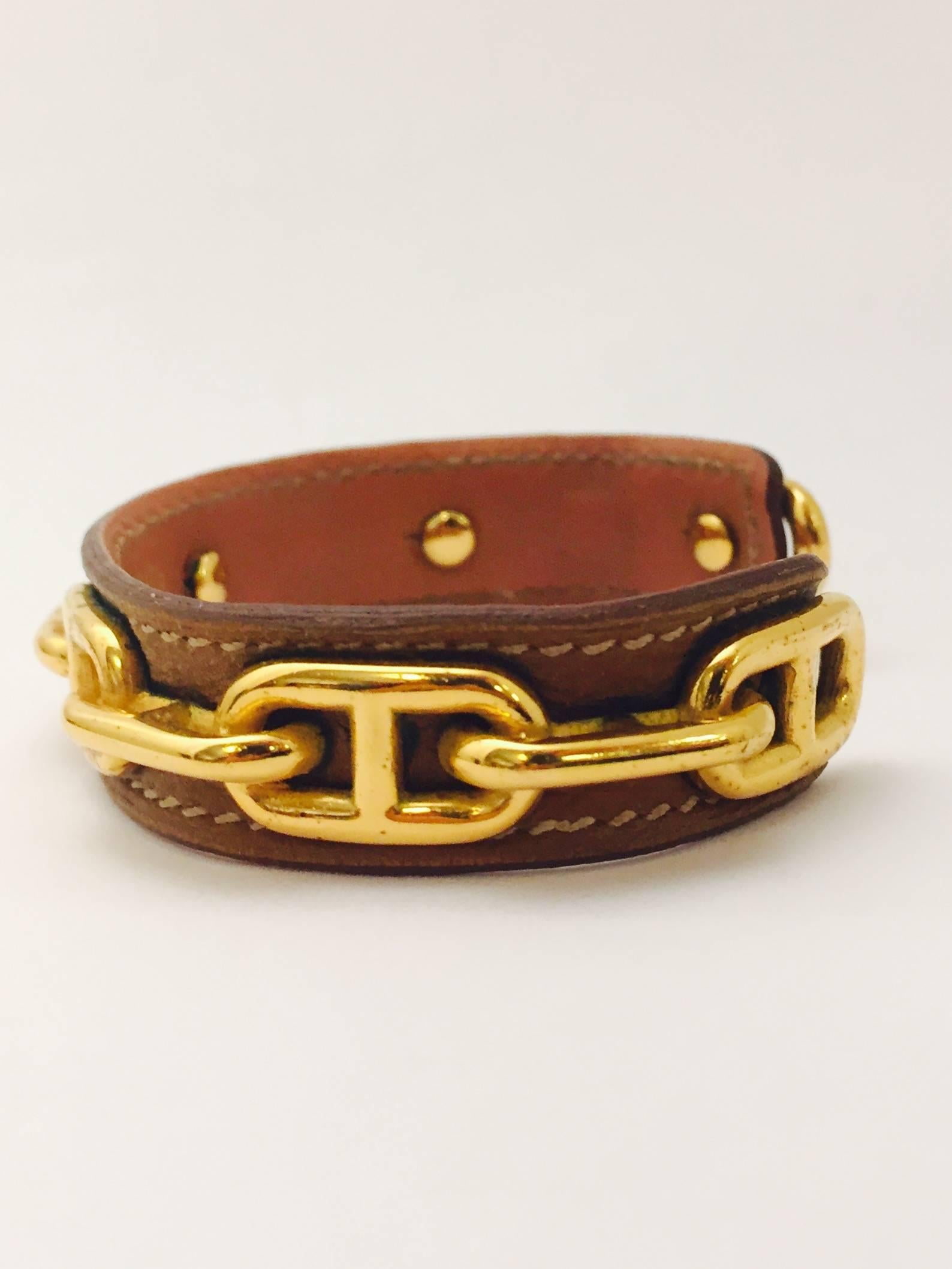 Hermes leather bracelet with Chaine d'Ancre (Anchor Chain) model, gold plated chain on brown leather and one link on the chain is signed Hermes on the top.  The bangle bracelet is oval shape with a 1