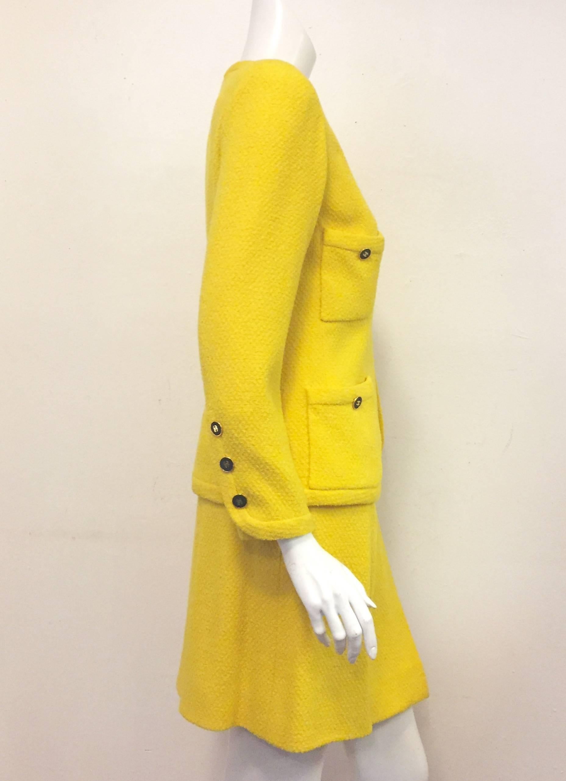 Chanel Boutique sunshine yellow wool skirt suit will lift your spirits and give you warmth during cold winter months.  This long sleeve suit features 4 bucket pockets and 4 gold tone and black CC buttons for closure.  Collarless, open concept jacket