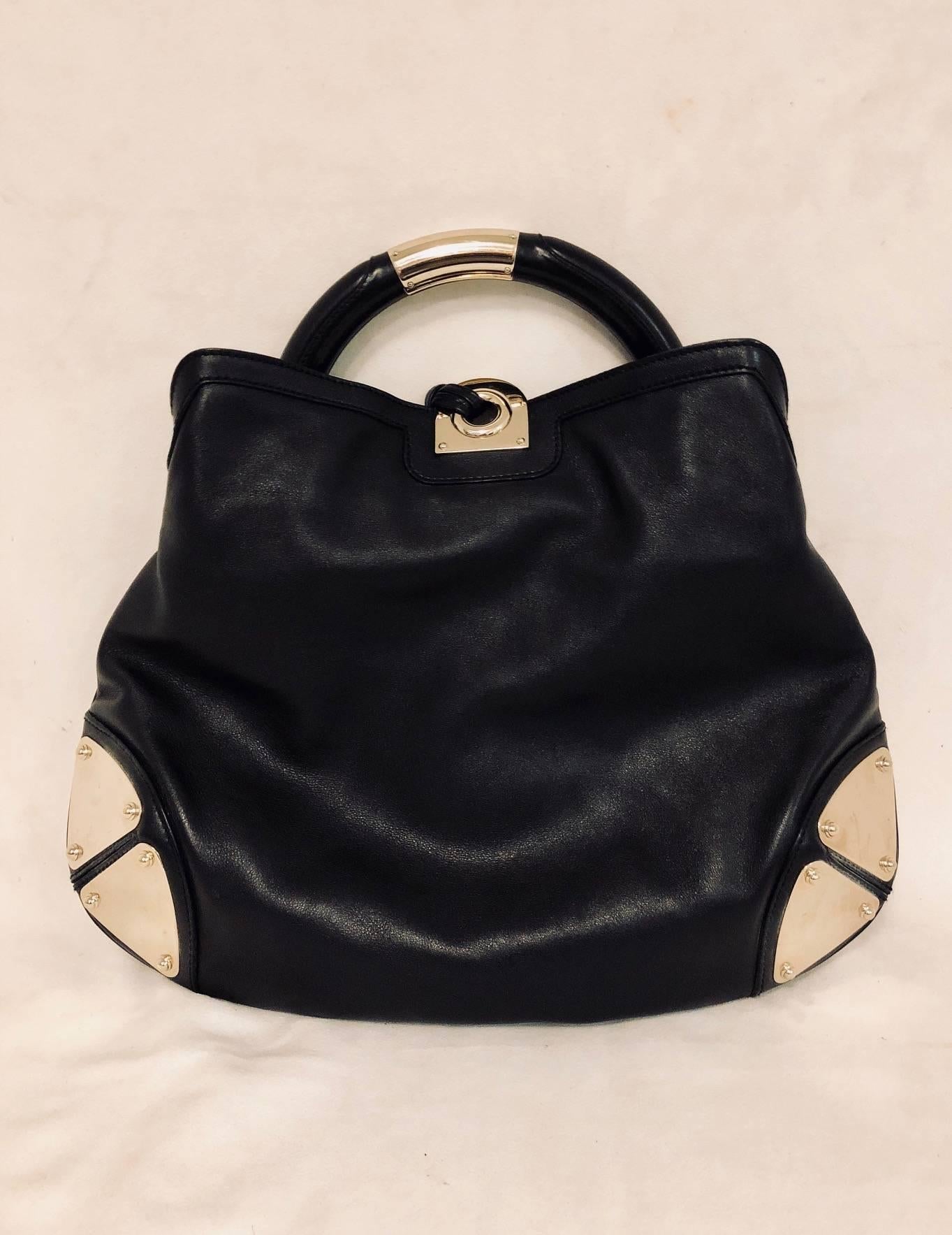 Guccissimo Gucci outstanding Indy handbag in black leather and 2 gold tone plaques on each side of bag for protection and glam.  One hard semi circular handle and one removable shoulder strap for practicality and comfort both with the same gold tone