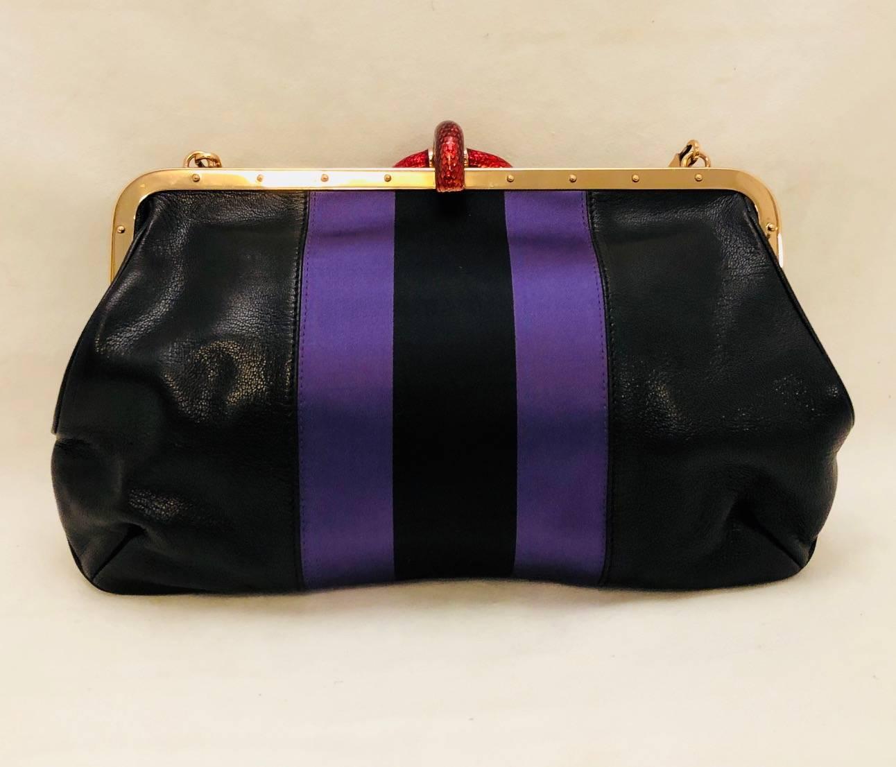 Gucci Tom Ford era designed this stylish and intricate black leather handbag with purple and black satin stripes across the middle and a red enamel snake with one large Swarovski crystal in its mouth for closure creating a whimsical captivating