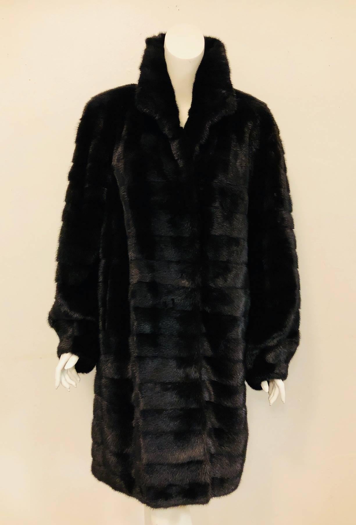 This outstanding black mink coat features shirt collar with 3 hook and eye closure and incorporates a metallic silk lining.  The silk lining's decor is a bit gothic with ornate twist and twirls in gold, beige and silver against a black backdrop. The