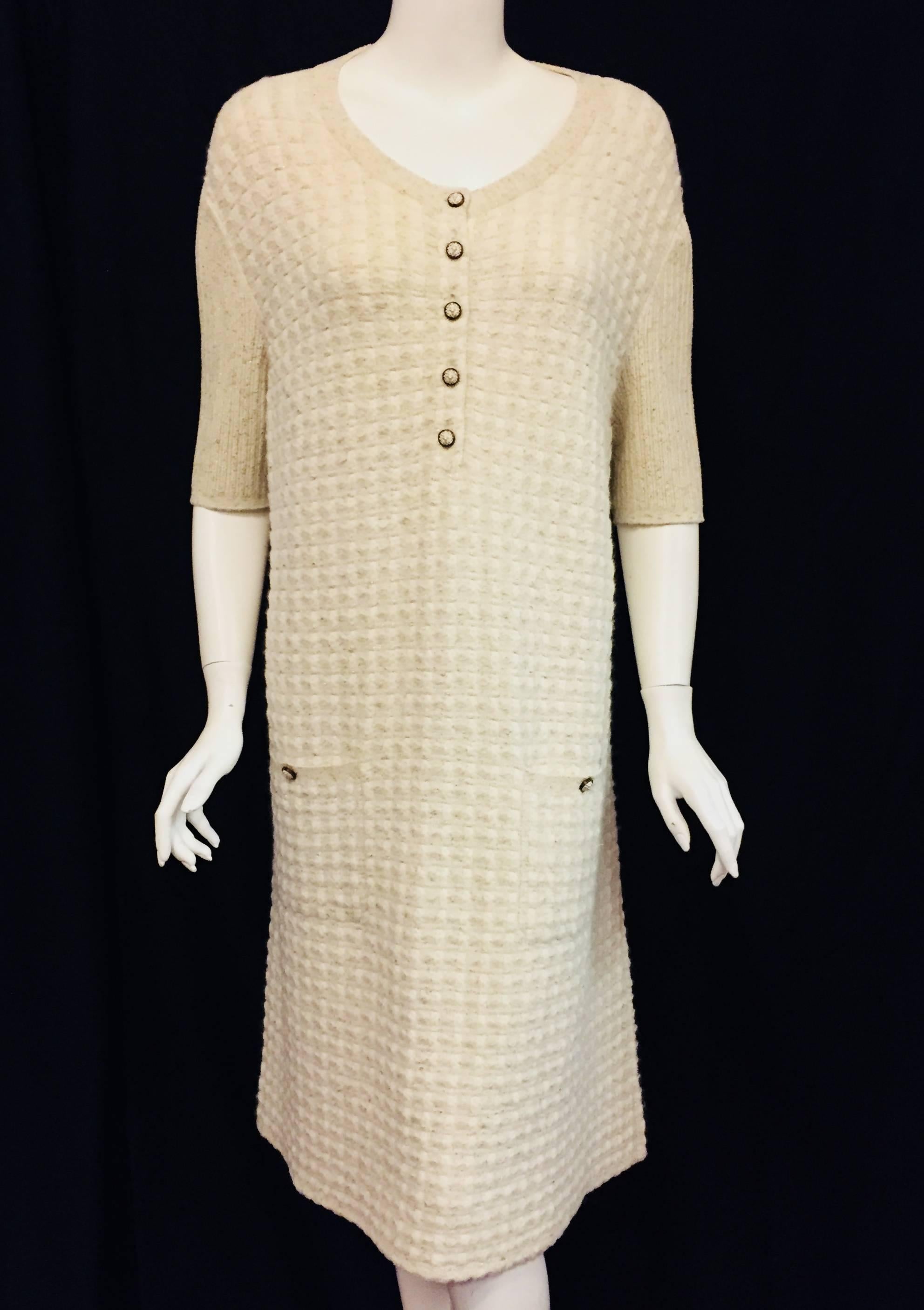 This Chanel ivory mohair, rayon and wool knit dress features 3/4 length sleeves and showcases 5 decorative Chanel buttons at front for closure.  This sheath dress is textured throughout and features gold tone threads allover.  Each patch pocket has