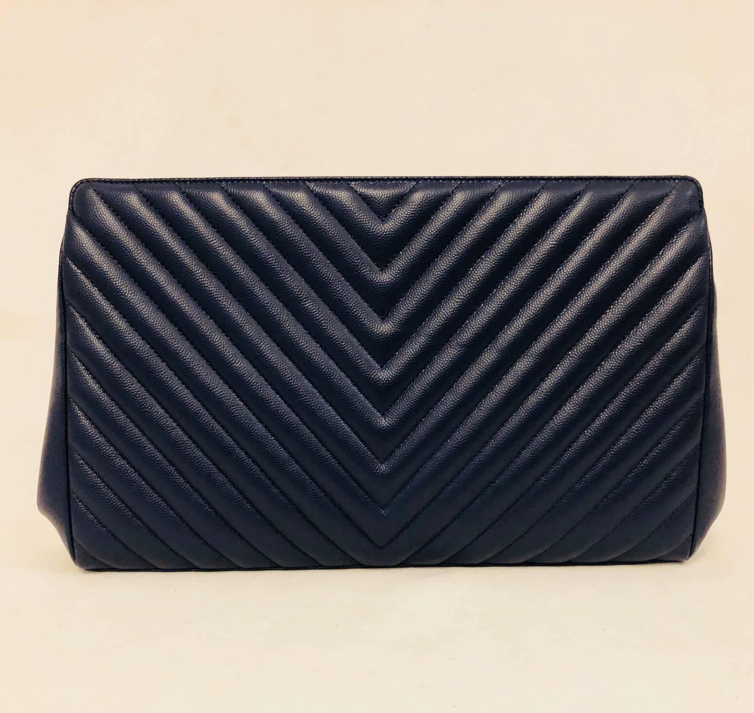 Fit for a lady, this Chanel frame clutch features chevron quilted textured leather, magnetic top closure, and external pocket with flap closure and turn lock access.  Silver tone hardware.  Luxurious navy lambskin lines external pocket and interior.