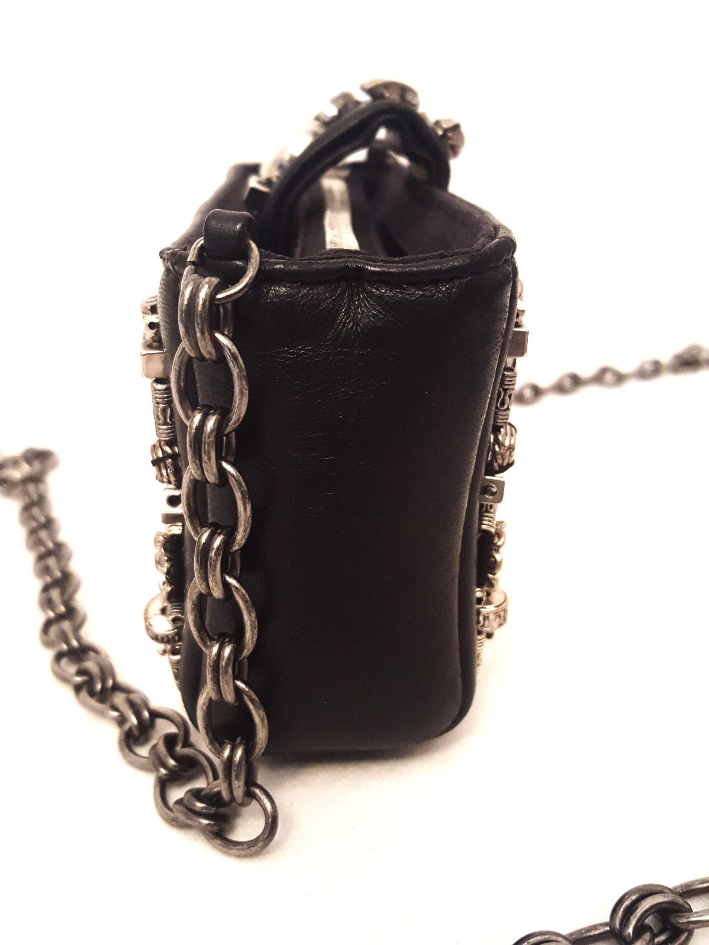 Chanel black leather with pewter tone metal enhanced trinkets at the front, back and on the base of this mini shoulder bag transform it into a veritable treasure!  The long chain strap, also, in pewter tone metal, not the typical Chanel braided