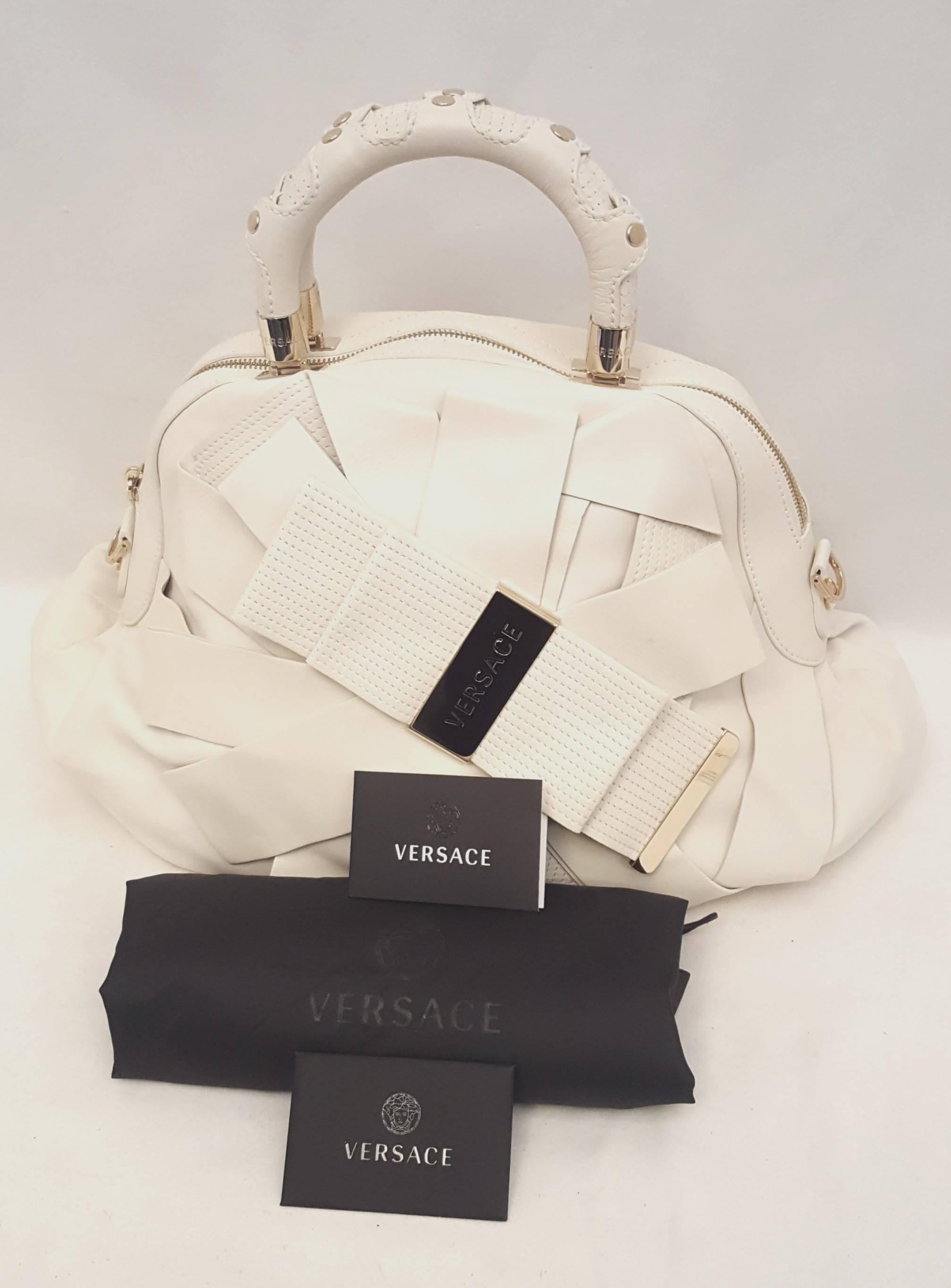 This stylish Versace ivory leather Venita bow satchel with wide bands of ivory leather some with trapunto stitching and a large Versace logo cinching bands together creates an attention getting bow at the front of this 2009 spring collection