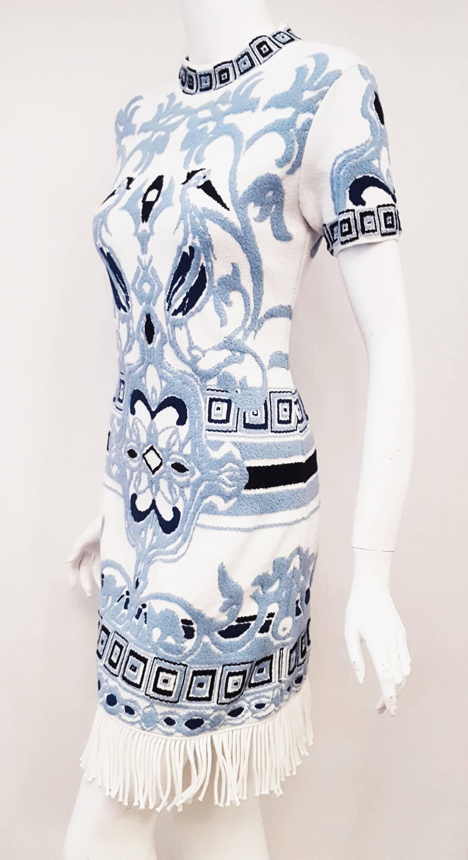 A delicate fringed hem Emilio Pucci vibrant blue and white mosaic motif with nature elements with a bit of African 
shapes adds vitality to this streamlined knit sheath dress.  With a classic mockneck collar and the short sleeve both repeating the