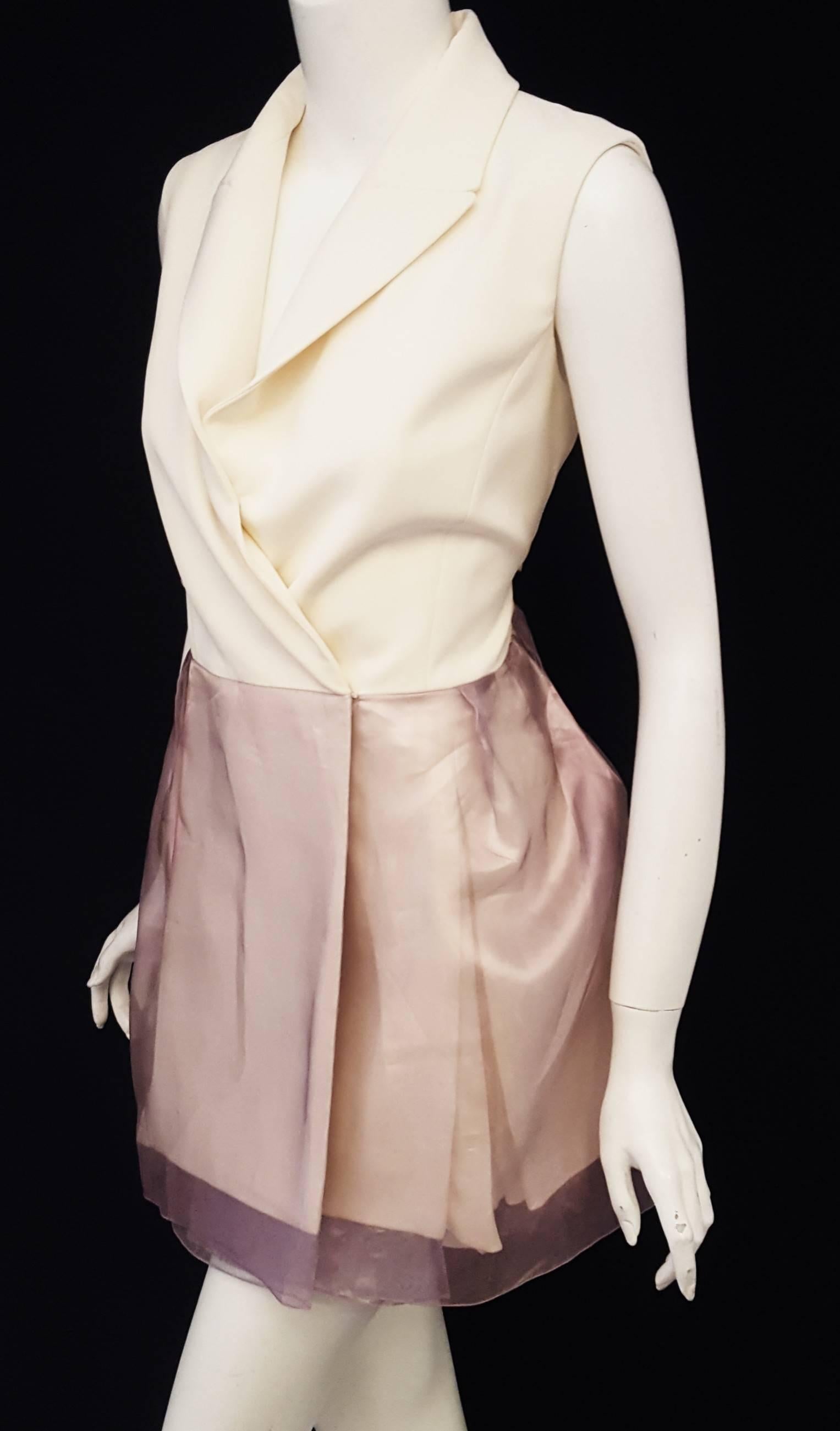 Christian Dior ivory and lavender silk wrap dress is sleeveless with notch collar.  This wrap dress has a silk organza lavender overskirt.  The skirt on the dress contains panels with pleated inserts and is cinched at the waist with 2 hidden buttons