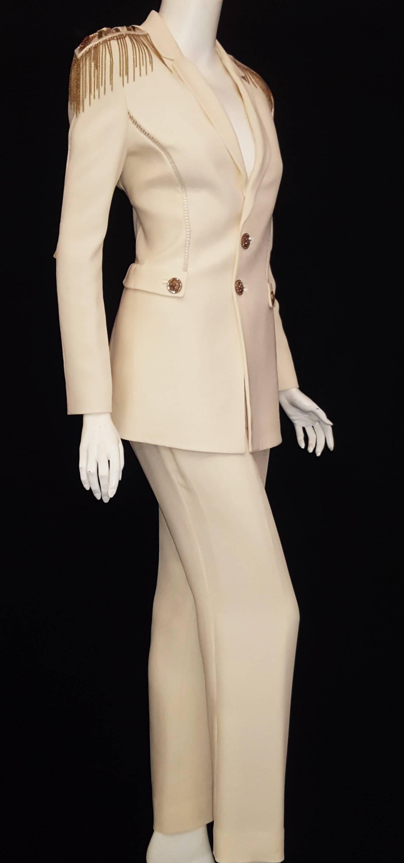 Versace cream pant suit hails from Milan's Fashion week for Autumn/Winter 2014.   This trouser suit is single breasted and to the hip and the pants that have a slight flair and front zipper for closure.  The cream color crisp trouser suit means