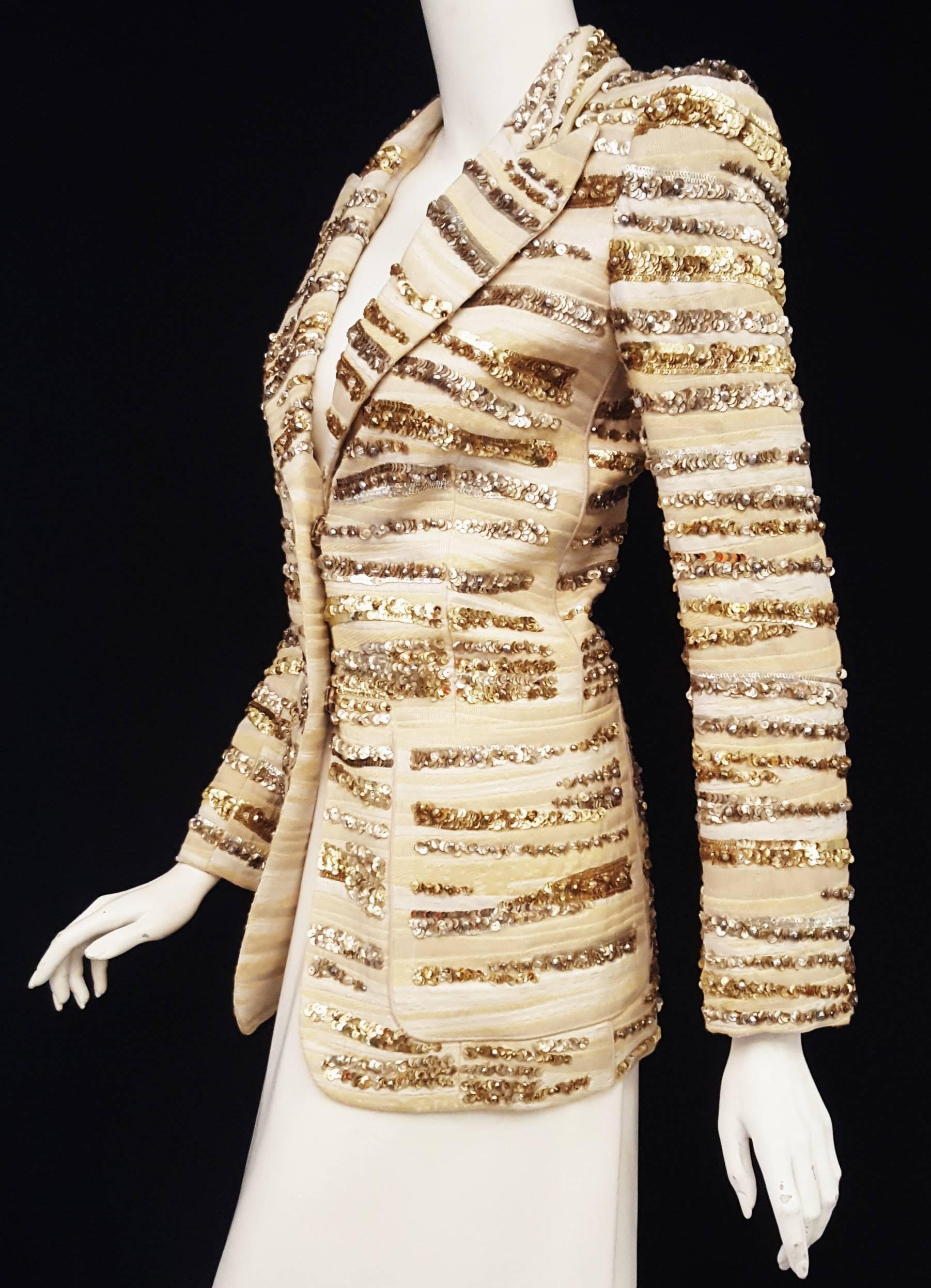 Marc Jacobs gold and silver tone sequins throughout the jacket features an undulating pattern camouflaging the beige and ivory striped brocade.  Jacket has notched collar with wide lapels, two front patch pockets and three crystal buttons on each