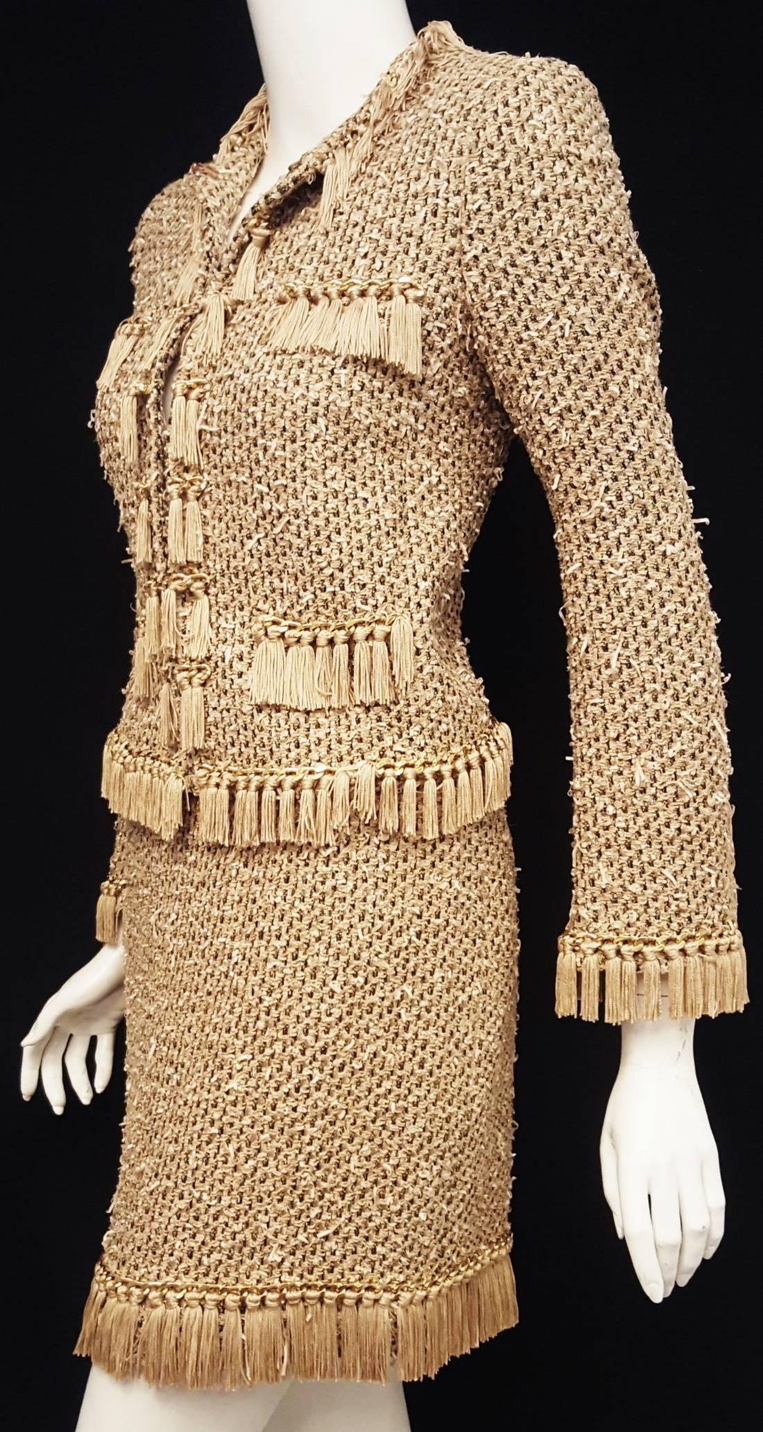 Moschino taupe, beige and black suit with tan fringe on jacket and skirt and a shiny gold tone chain is intricately decorated.  The fabric has woven into it tiny ribbons in ivory that are gently distressed giving the fabric a more textured look. 