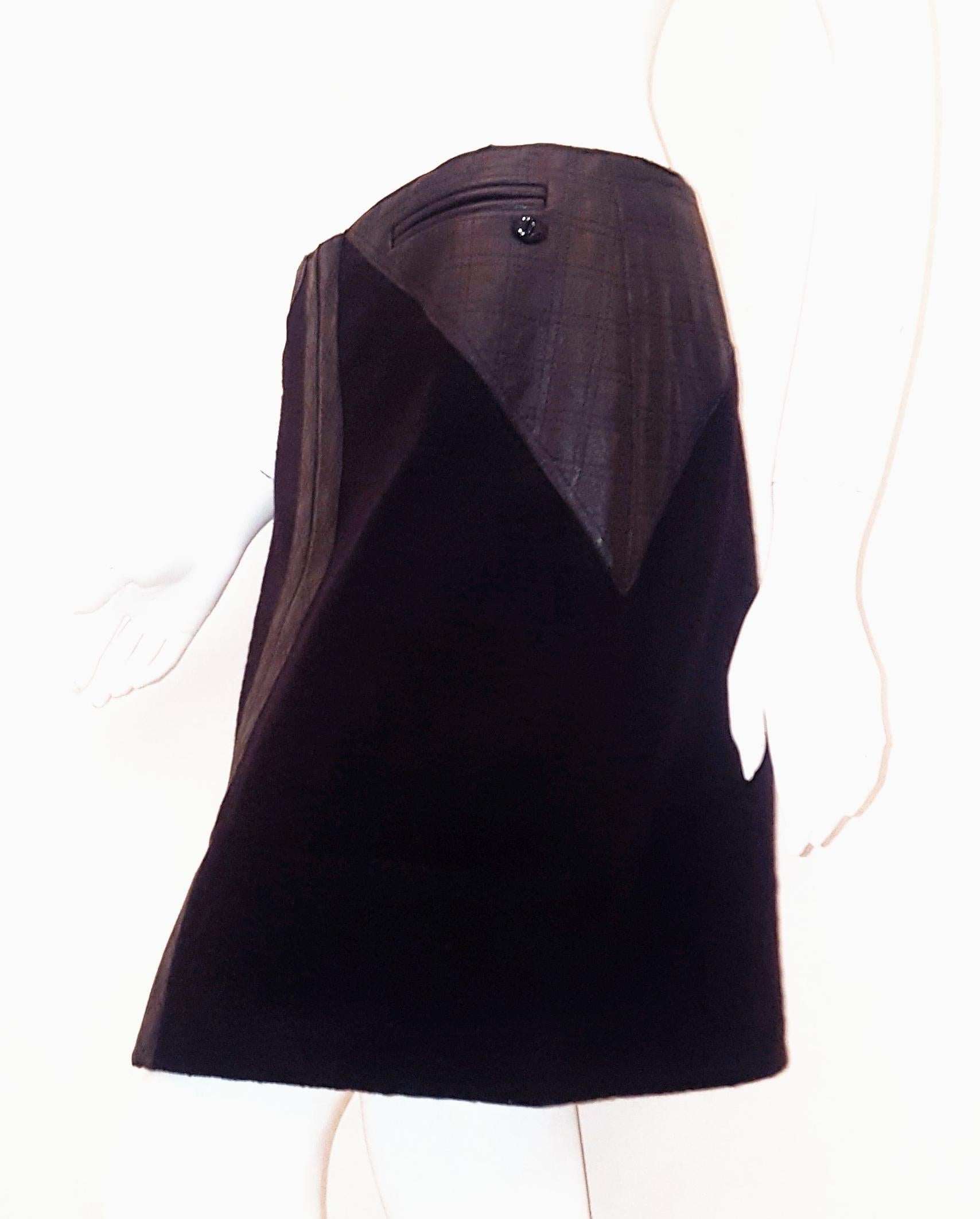 Chanel black wool skirt features triangle leather trim at the side of the skirt at the hip.  Two leather plackets can be found at front of skirt with a slit at hem.  Two faux pockets at front and the iconic Chanel CC plaque at one side.  For closure